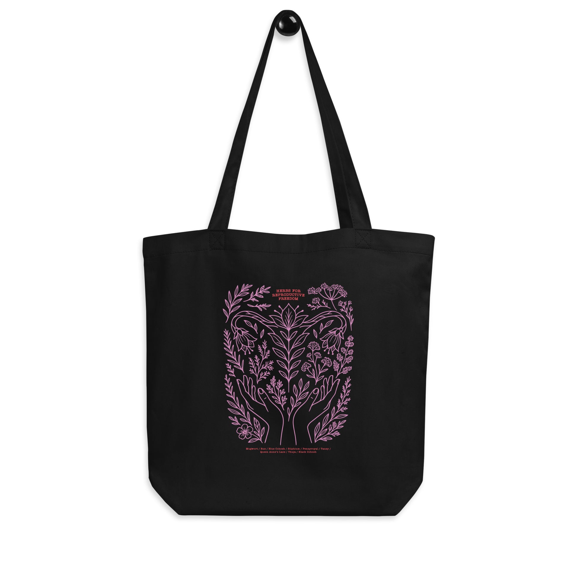 Front view of the black “Herbs for Reproductive Freedom” eco tote bag printed with pink herbal artwork symbolizing healing, protection, and choice. Designed by Blue Wave USA.
