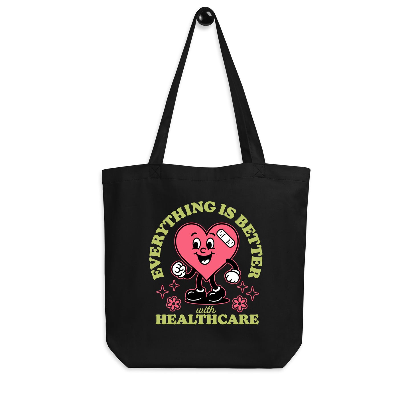 Black “Everything Is Better with Healthcare” tote bag hanging by its straps, featuring the heart design and pastel green text.