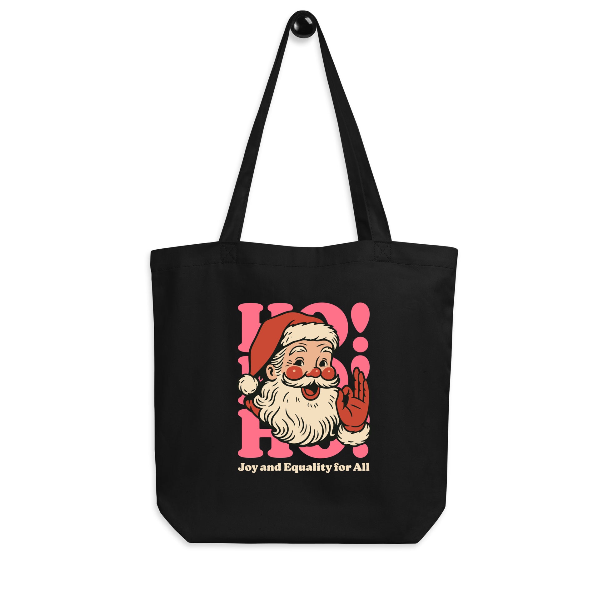 Black tote bag displayed hanging by its long shoulder straps, showing the full “Joy and Equality for All” Santa design on the front.