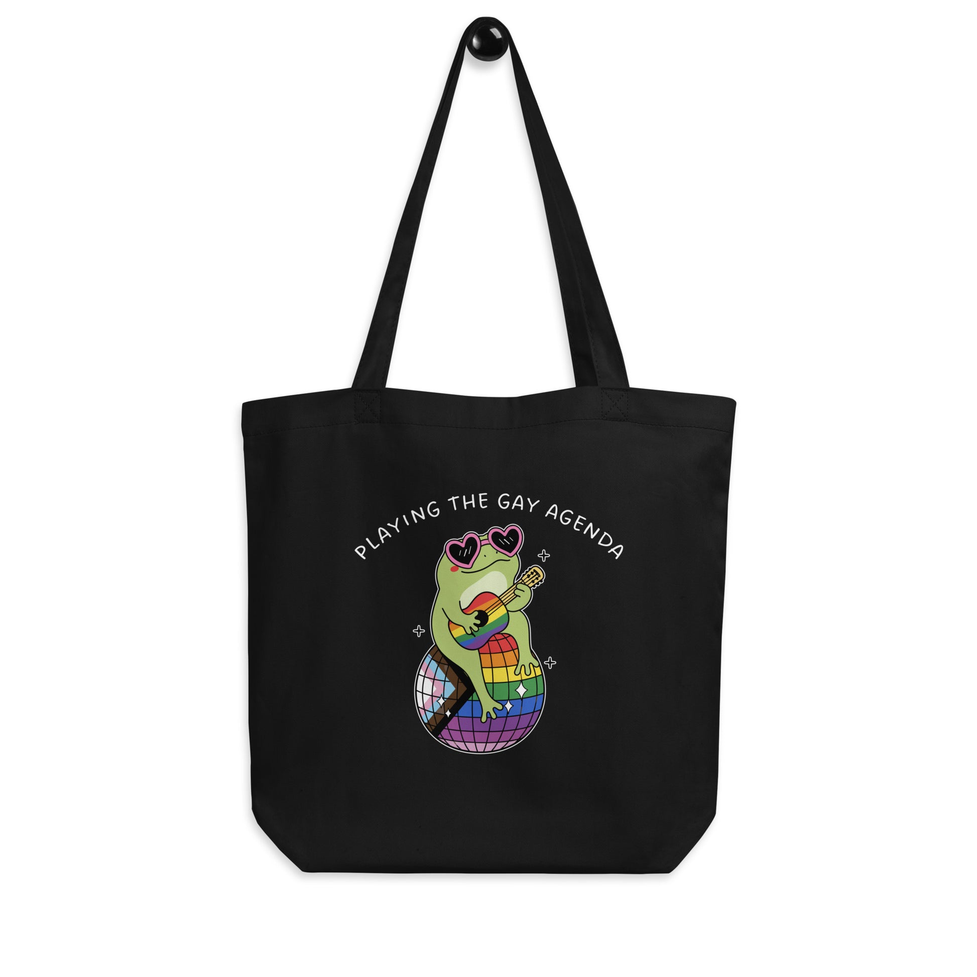 Black reusable tote bag displaying a retro disco frog in platform boots with rainbow accents and “Playing the Gay Agenda” pride-inspired message.