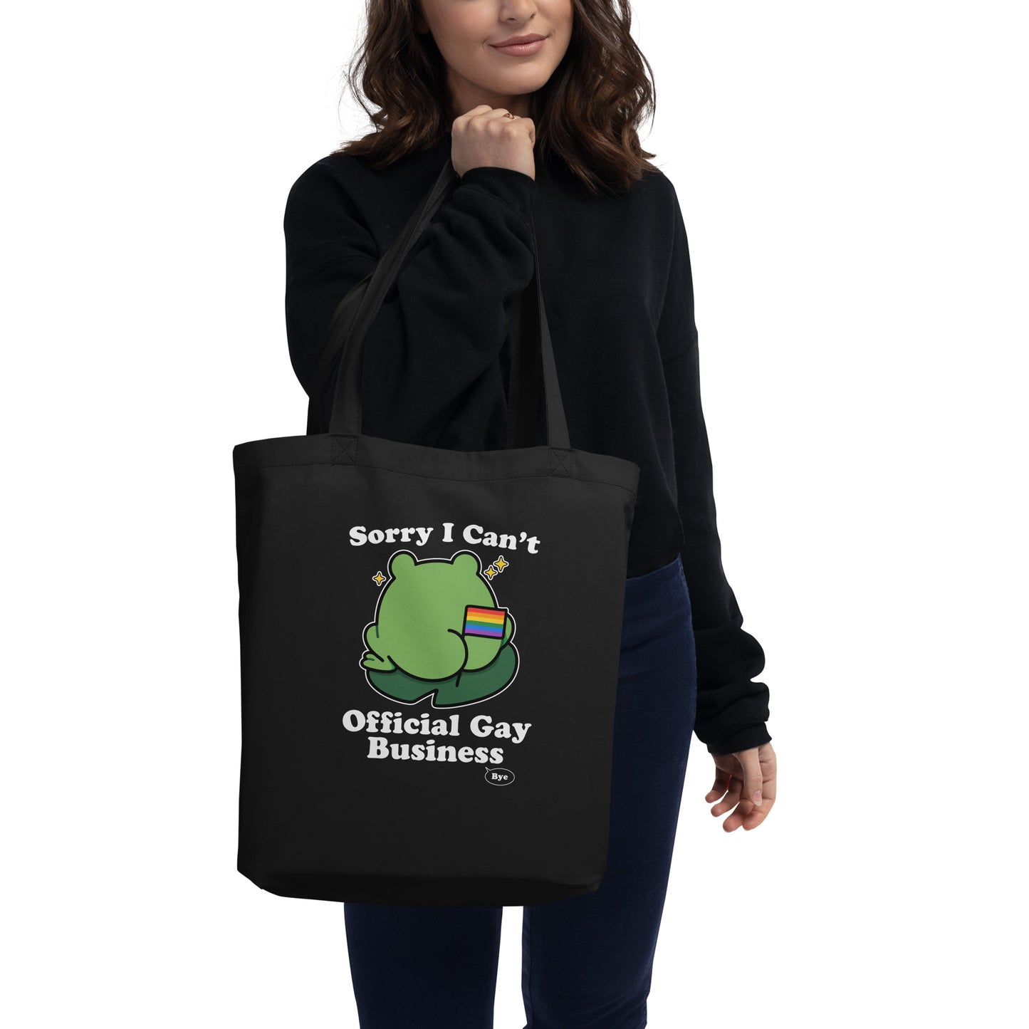 Person carrying a black tote bag featuring a frog holding a rainbow flag with playful “Sorry I Can’t. Official Gay Business. Bye.” design.