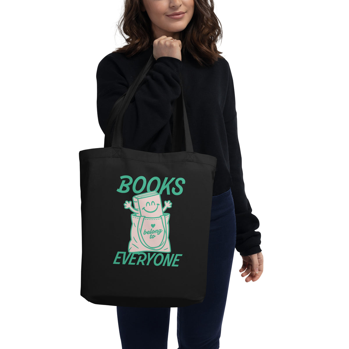 Person carrying a black eco tote bag featuring the “Books Belong to Everyone” design supporting libraries and the freedom to read.