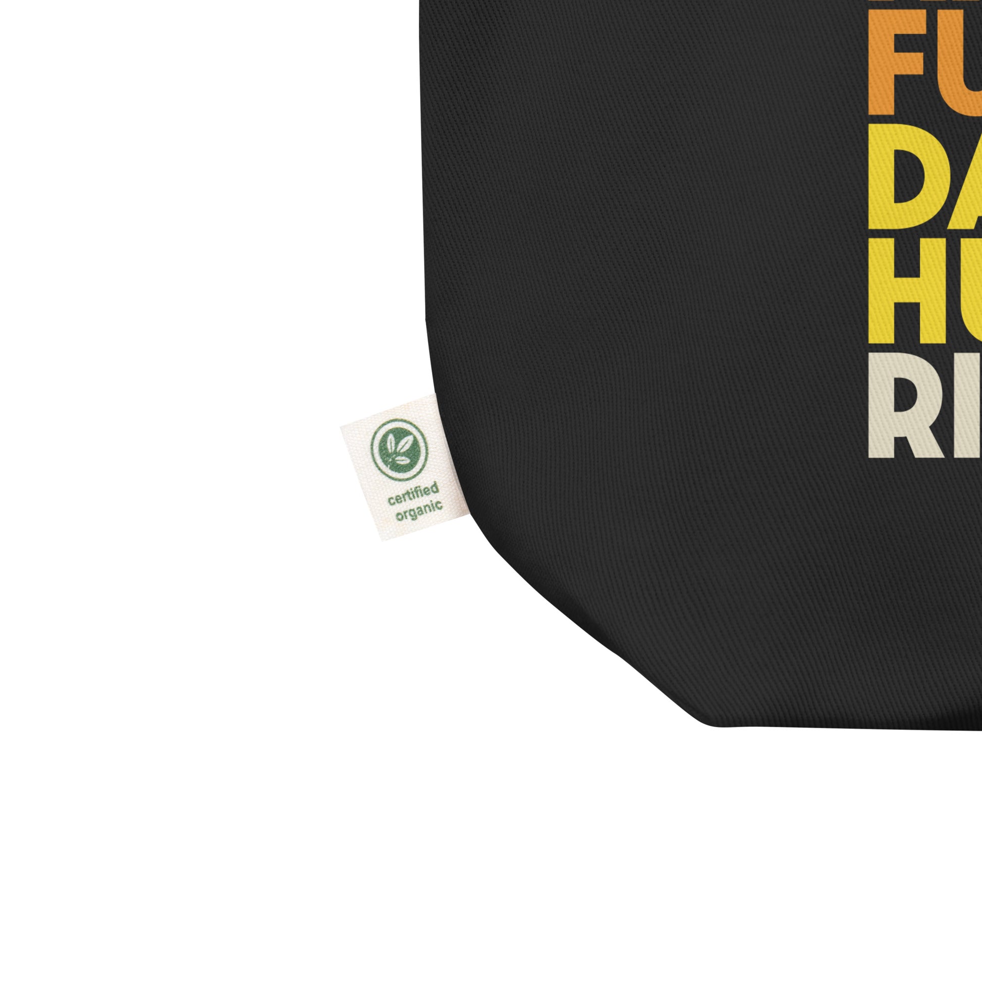 Close-up of the eco-friendly fabric tag on the black “Girls Just Wanna Have Fundamental Human Rights” tote bag, showing sustainable cotton material and print detail. Designed by Blue Wave USA.