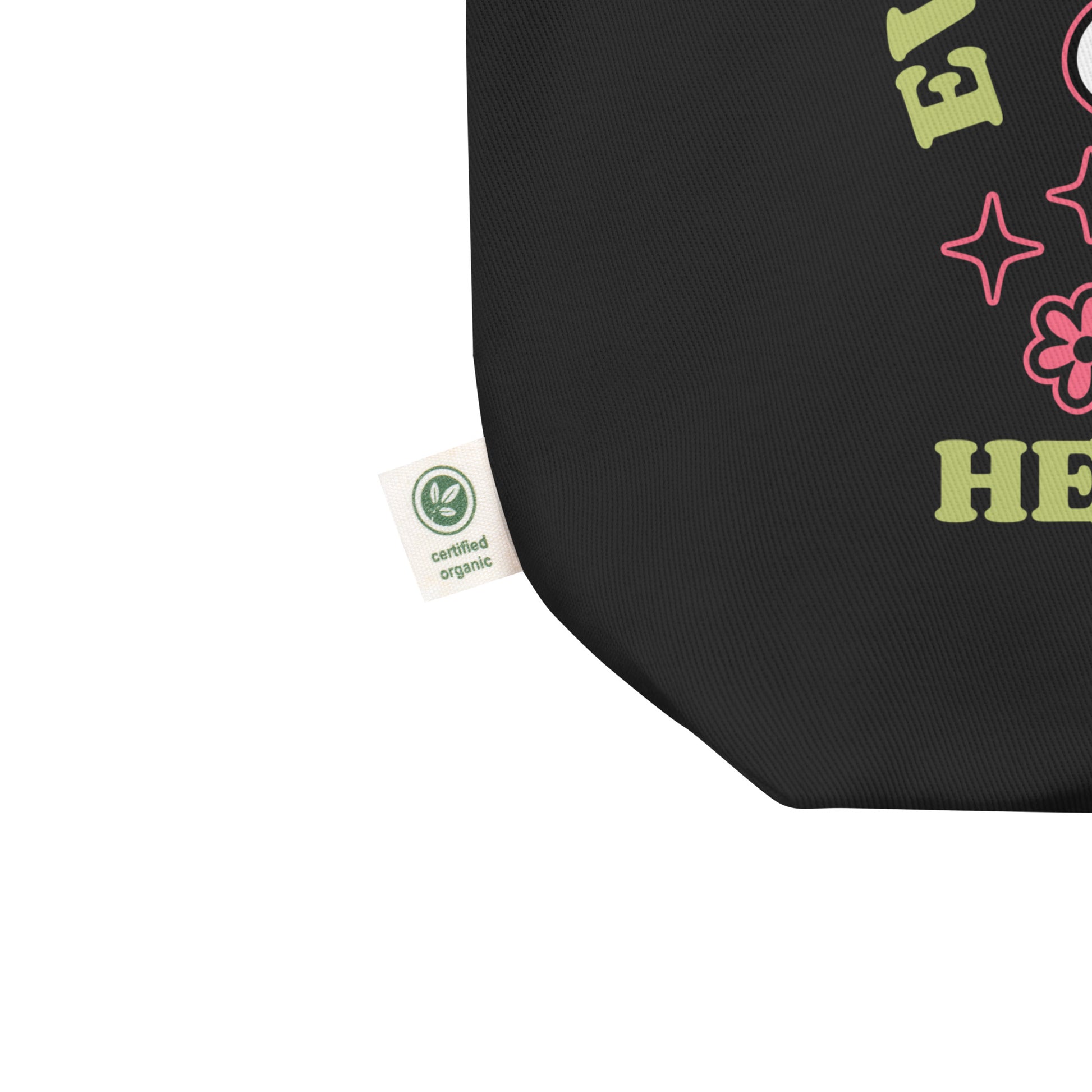 Detail of the organic cotton tote bag corner showing eco-friendly certification tag and part of the “Everything Is Better with Healthcare” print. Created by Blue Wave USA.