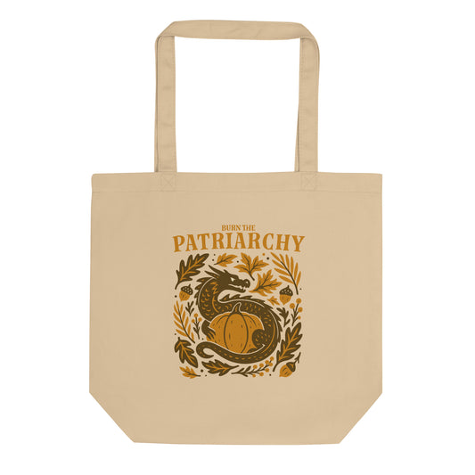 Beige eco tote bag with “Burn the Patriarchy” dragon and pumpkin design, feminist Thanksgiving print with acorns and leaves.