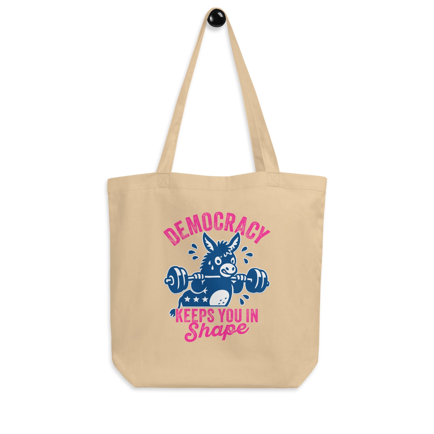 Natural canvas tote bag displaying blue donkey barbell artwork with pink democracy fitness phrase, bold civic humor accessory for errands, books, and market trips.