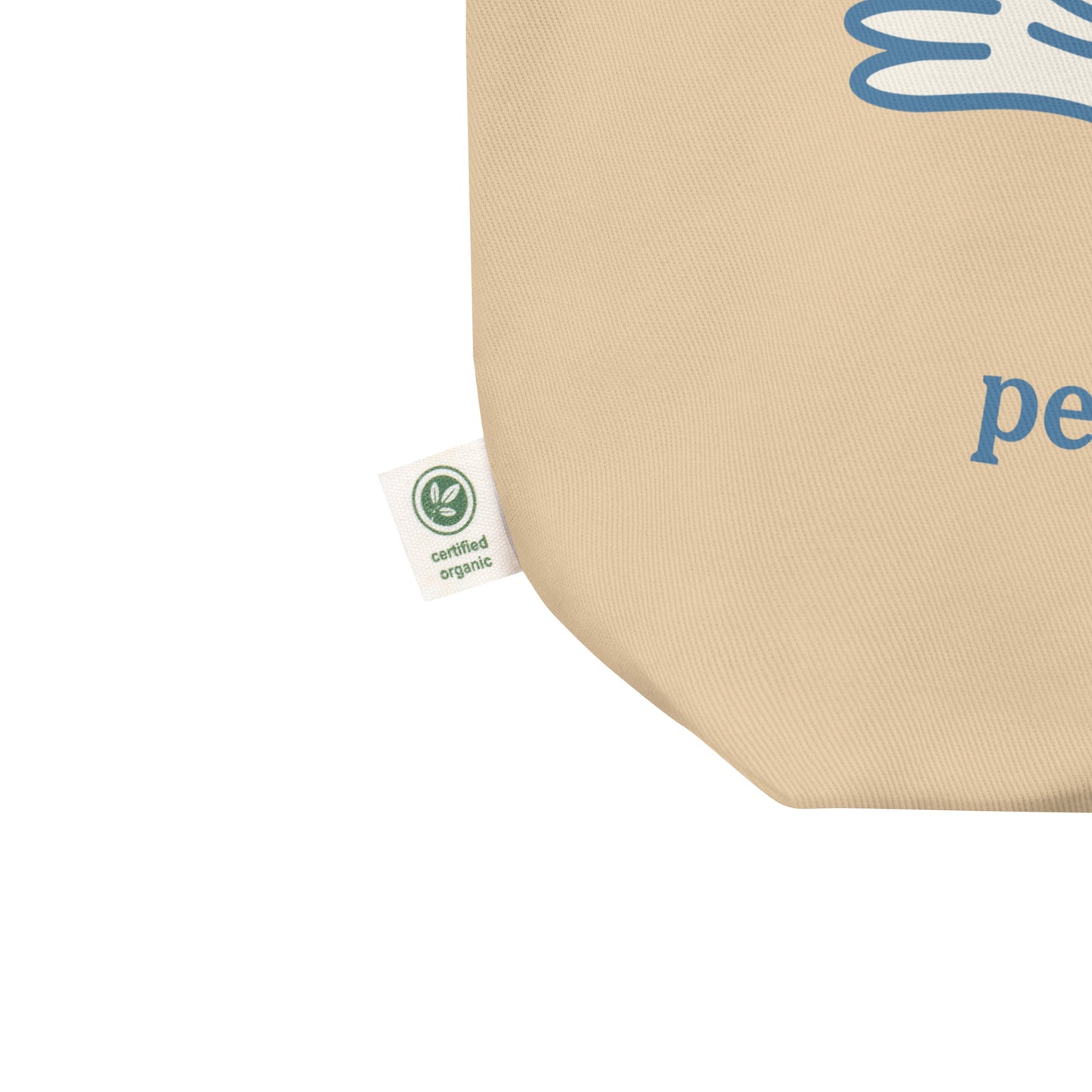 Close-up eco tote corner showing natural canvas texture with partial blue dove illustration and visible “peace over war” text detail.
