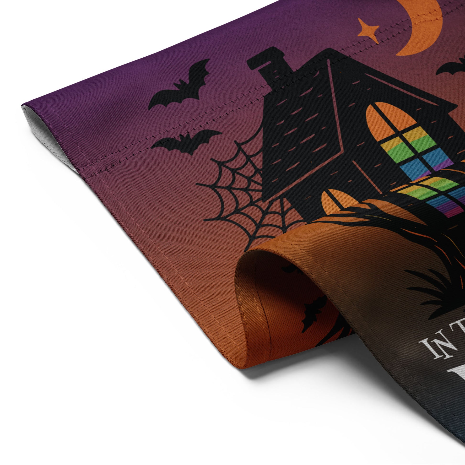 Angled close-up of the “In This House We Believe in Equal Rights” Halloween garden flag showing haunted house design, bats, and crescent moon.