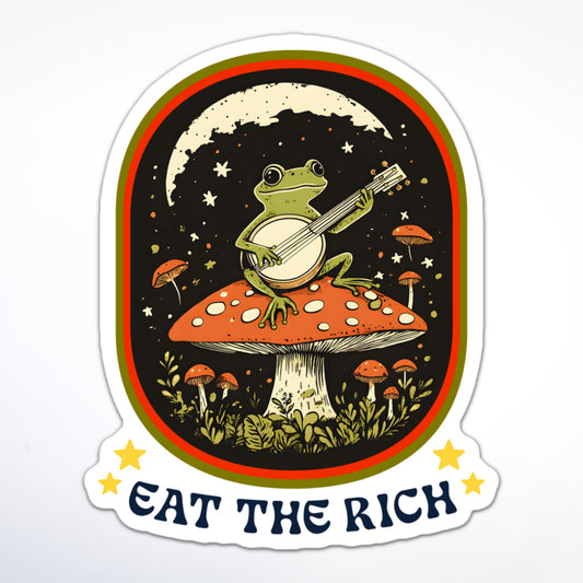 Cottagecore-inspired anti-capitalism sticker with a banjo-playing frog atop a toadstool and protest slogan “Eat The Rich.”