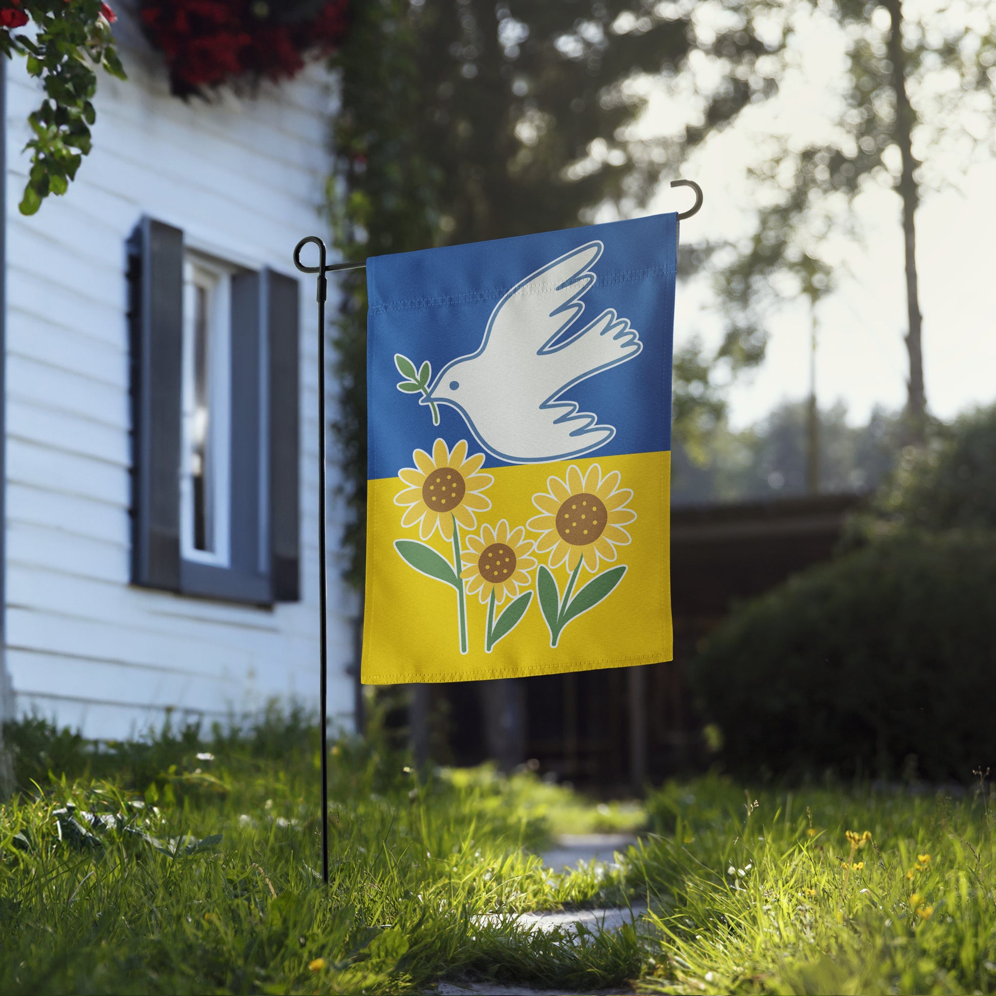 Progressive Ukraine Solidarity garden flag with dove and sunflower design, shown outdoors in front of a house.