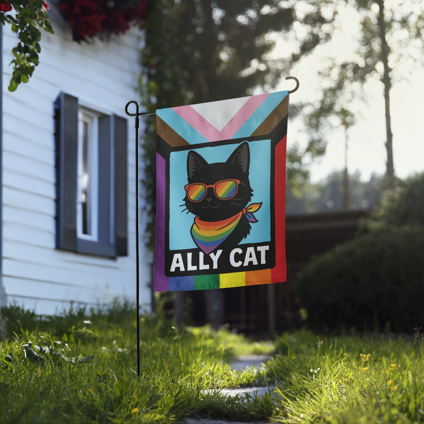 Outdoor lifestyle photo of an LGBTQ+ ally garden flag near a home, showing a rainbow-accented cat illustration and the phrase “ALLY CAT,” by Blue Wave USA.