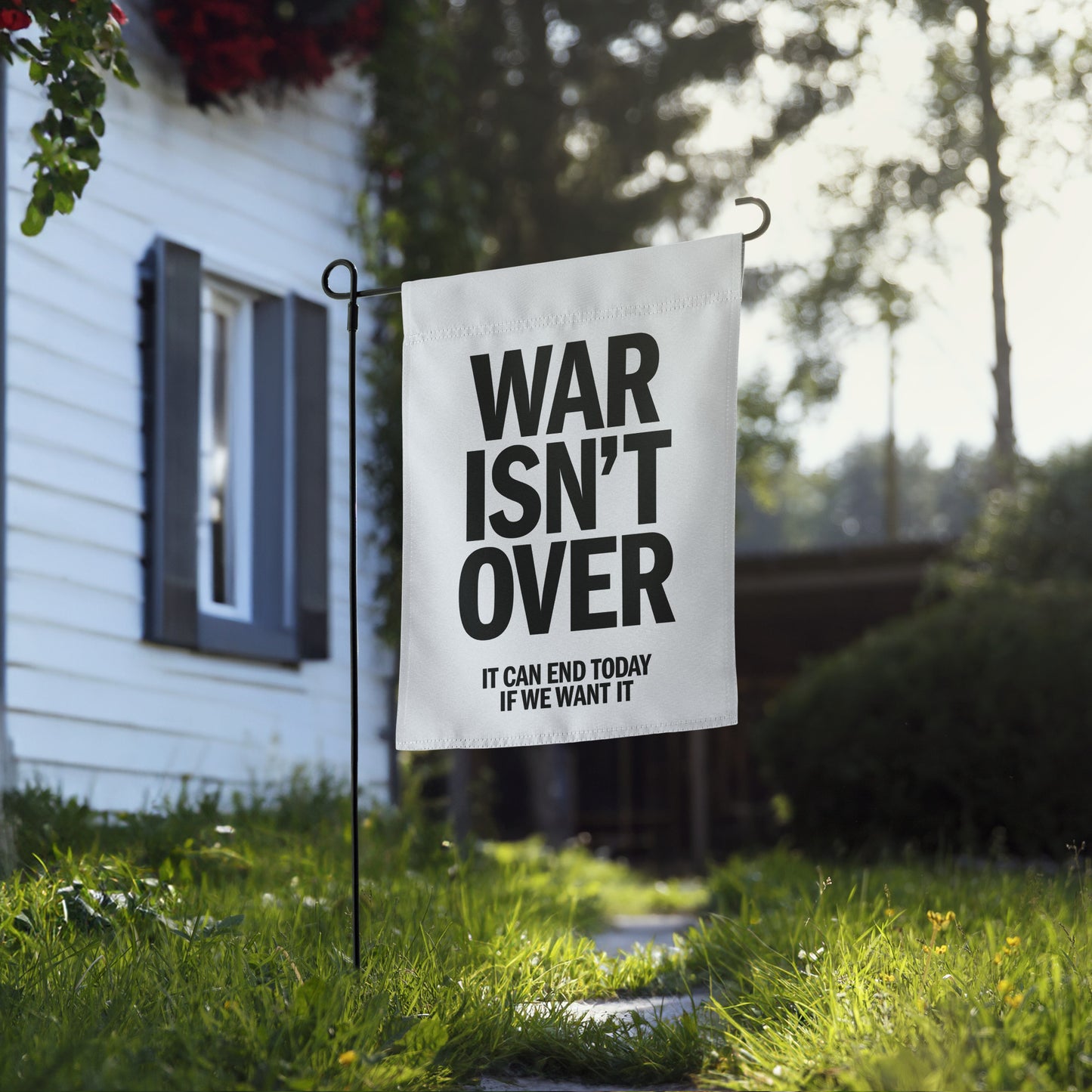 Blue Wave USA garden flag displayed near home walkway, showcasing “WAR ISN’T OVER” typography with peace-forward message about ending conflict today.