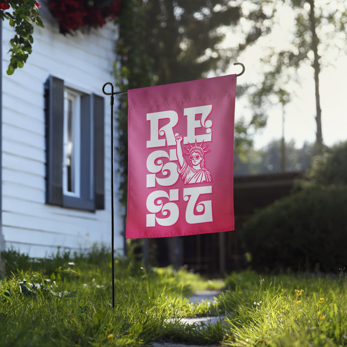Blue Wave USA garden flag displayed near home walkway, showcasing retro pink “RESIST” design with Statue of Liberty artwork and protest decor styling.