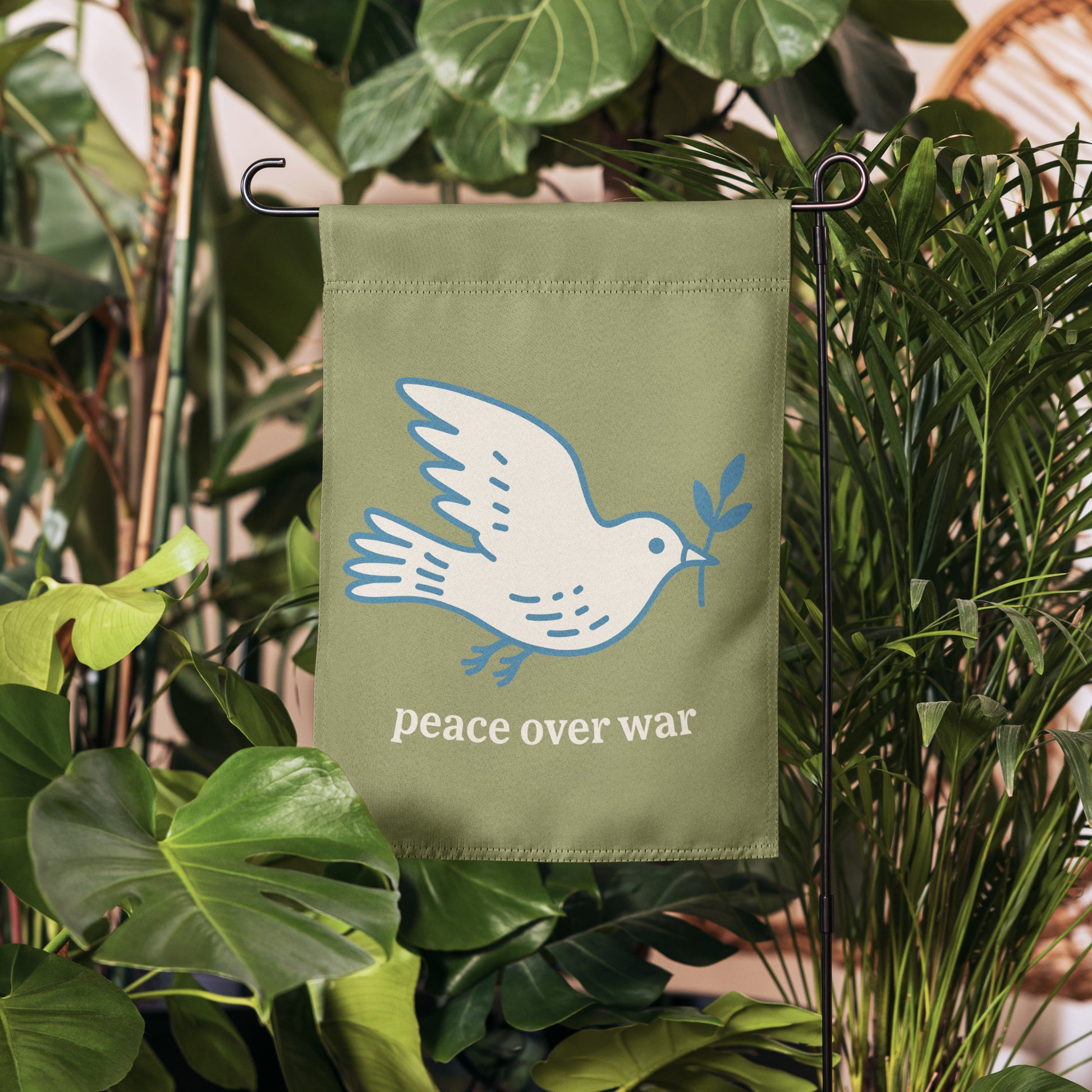 Blue Wave USA garden flag displayed among greenery, showcasing dove peace artwork and “peace over war” wording in calm justice-focused yard decor.