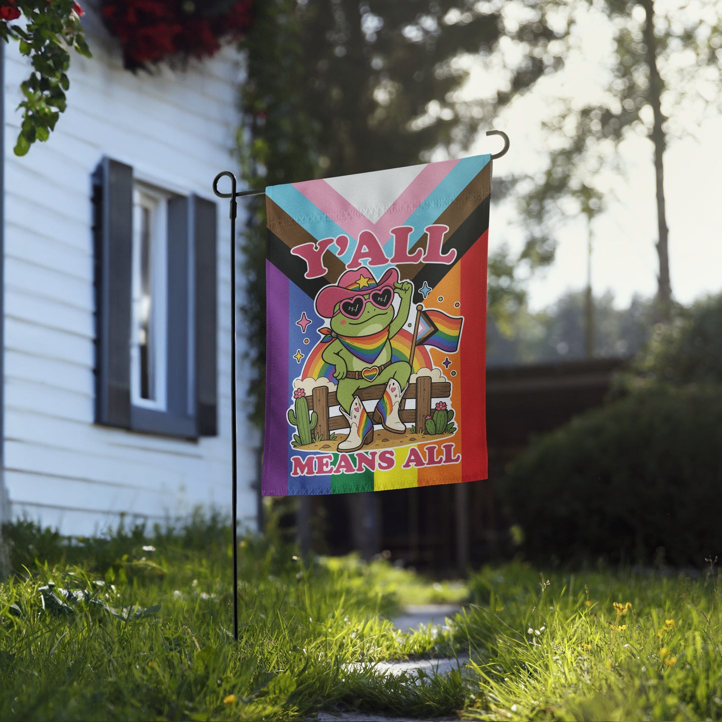 LGBTQ+ pride garden flag displayed outdoors, showcasing a cheerful cowboy frog, rainbow flag details, and welcoming “Y’All Means All” artwork celebrating inclusion and community.