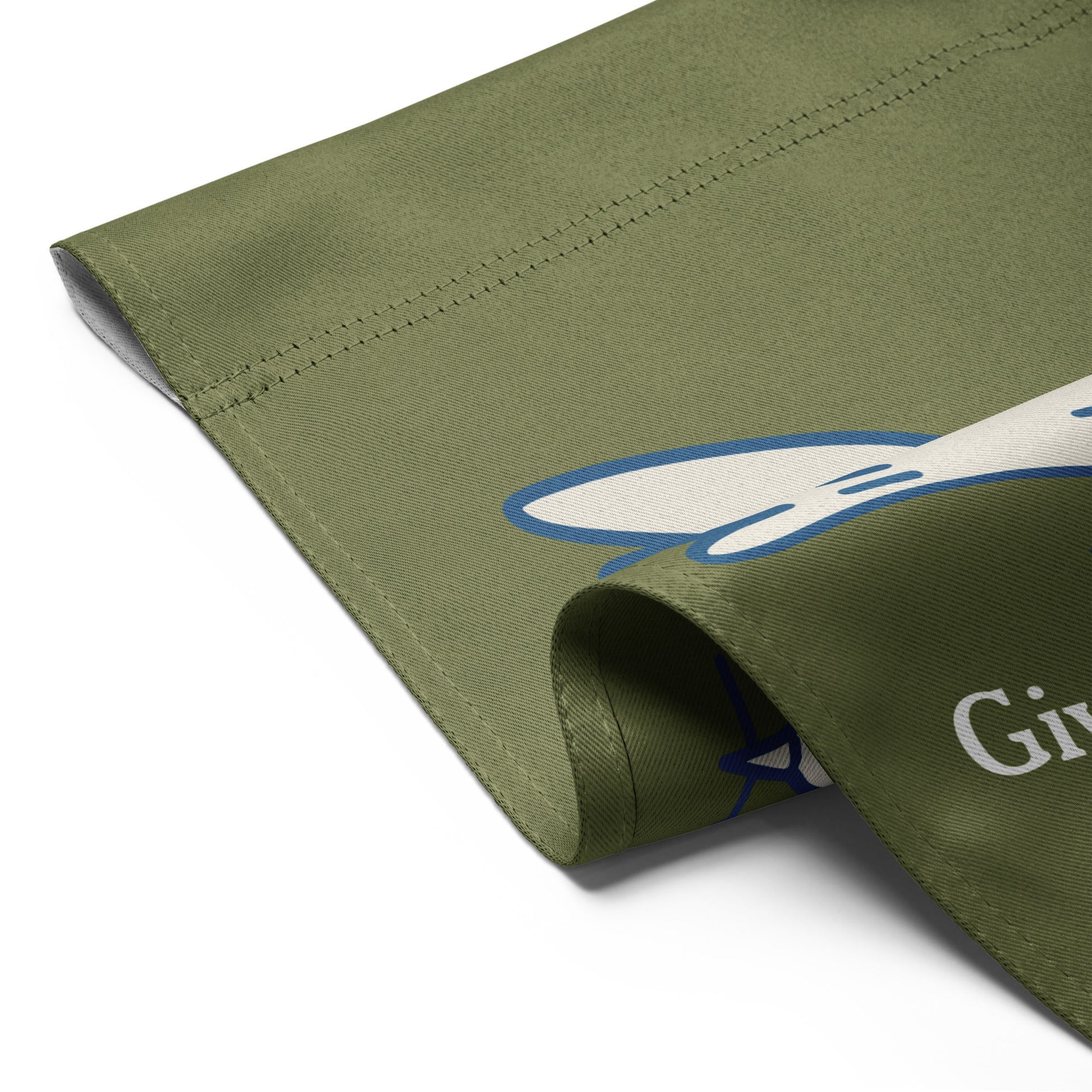 Close-up folded garden flag corner showing olive green fabric texture with partial white dove artwork and visible “Give Peace a Future” lettering.