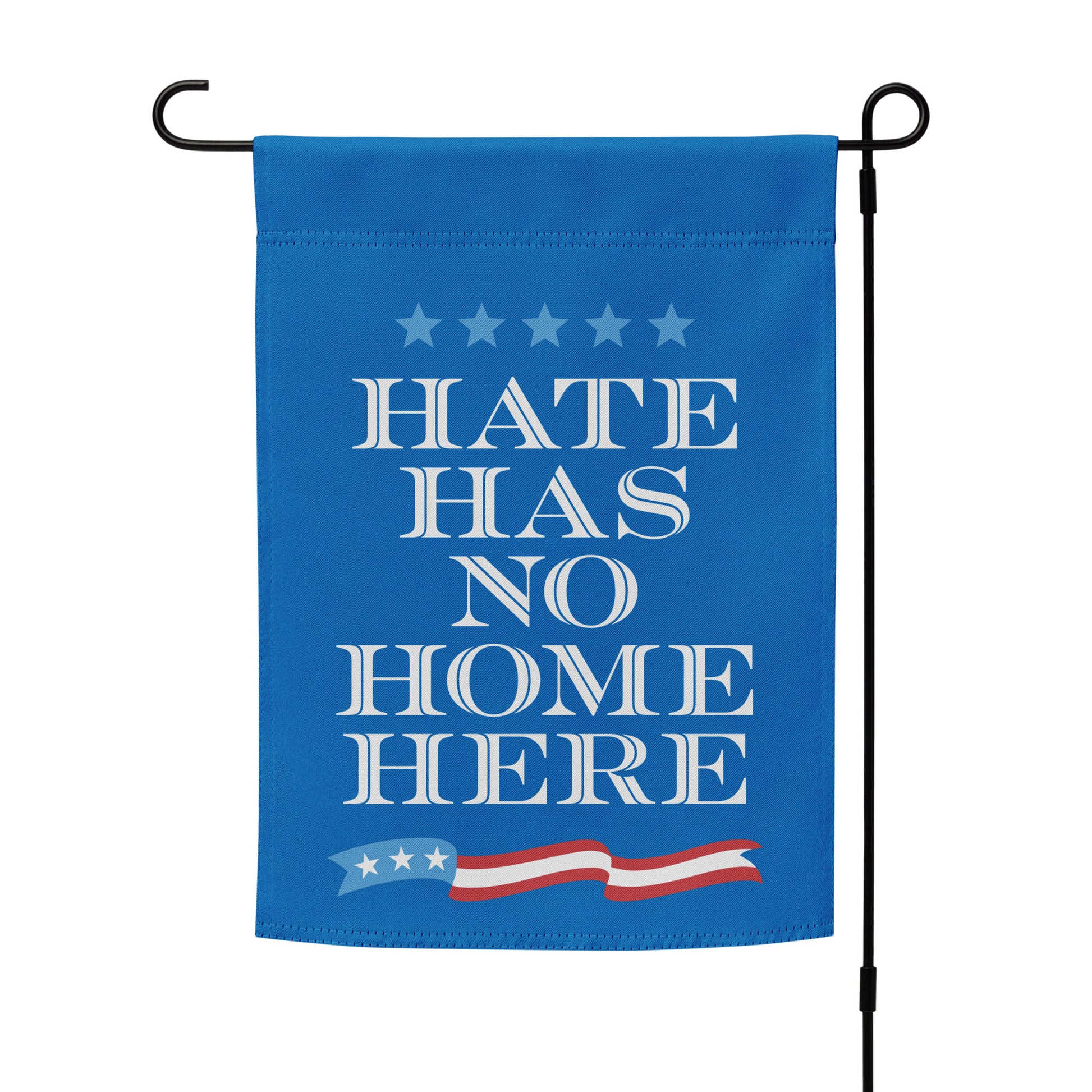 Garden flag displayed on black metal stand, blue background with bold white “HATE HAS NO HOME HERE” message, progressive yard decor from Blue Wave USA.