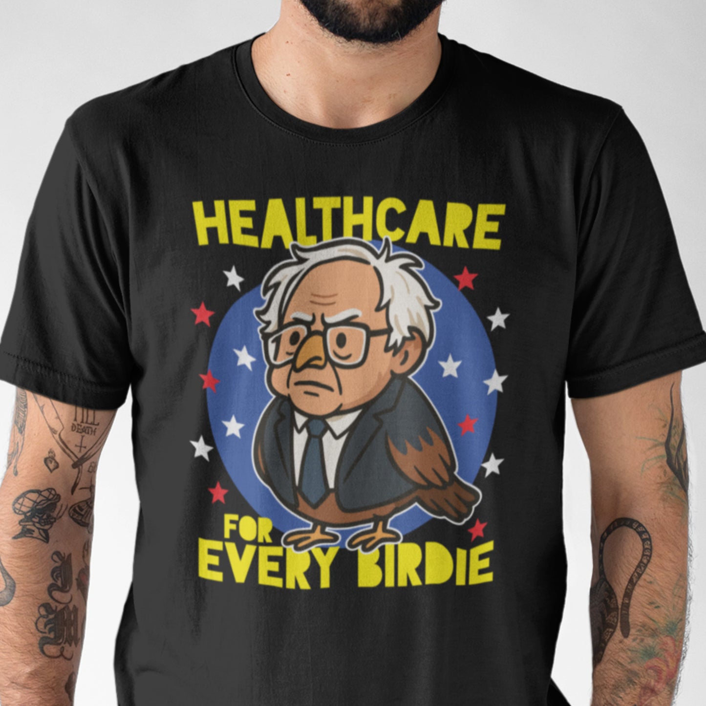 Man wearing black t-shirt with cartoon bird character and bold “Healthcare for Every Birdie” text, colorful political graphic design promoting universal healthcare message.