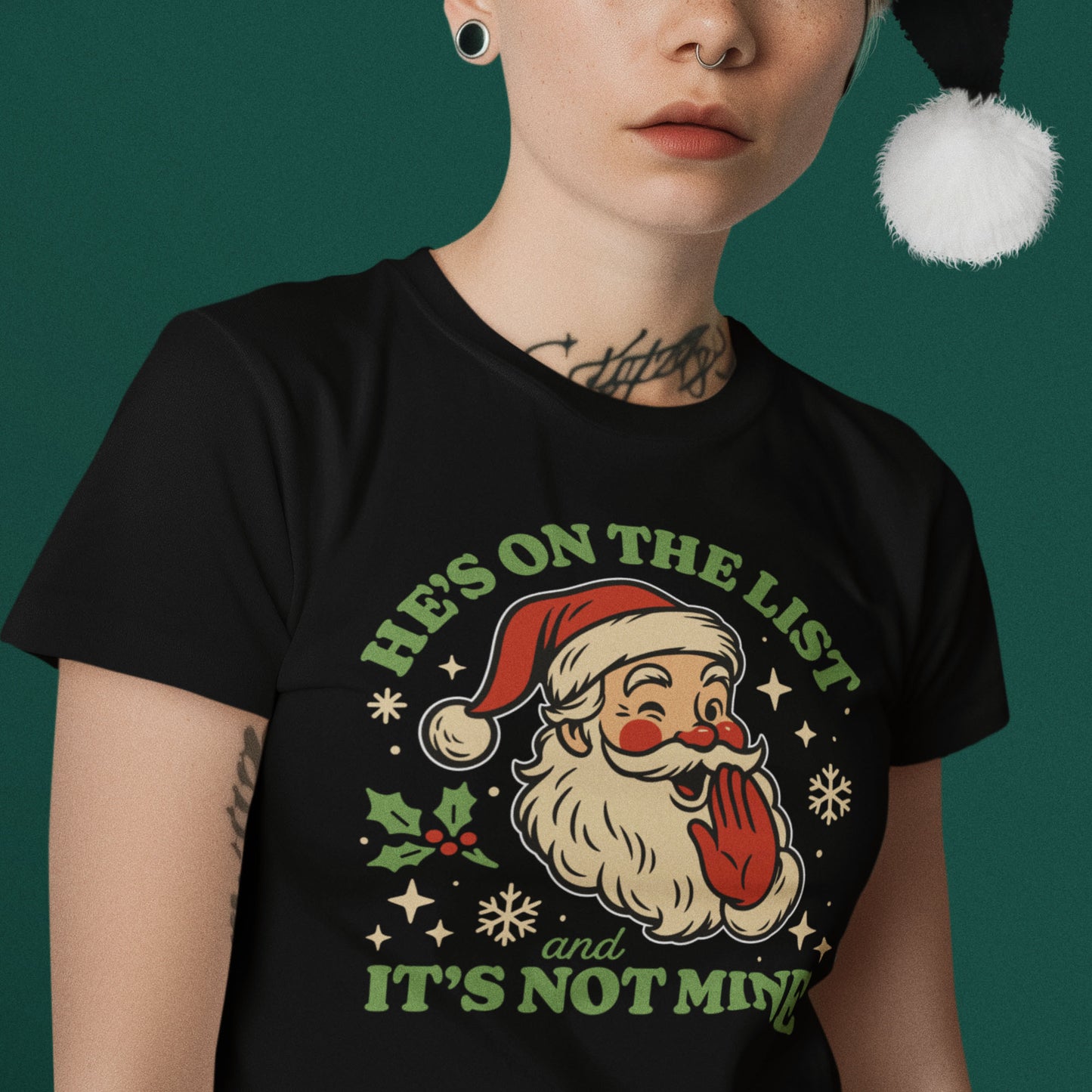 Person wearing a women’s black tee with the playful retro Santa “He’s On the List & It’s Not Mine” design, styled with a festive pom-pom hat. A fun seasonal look from Blue Wave USA.