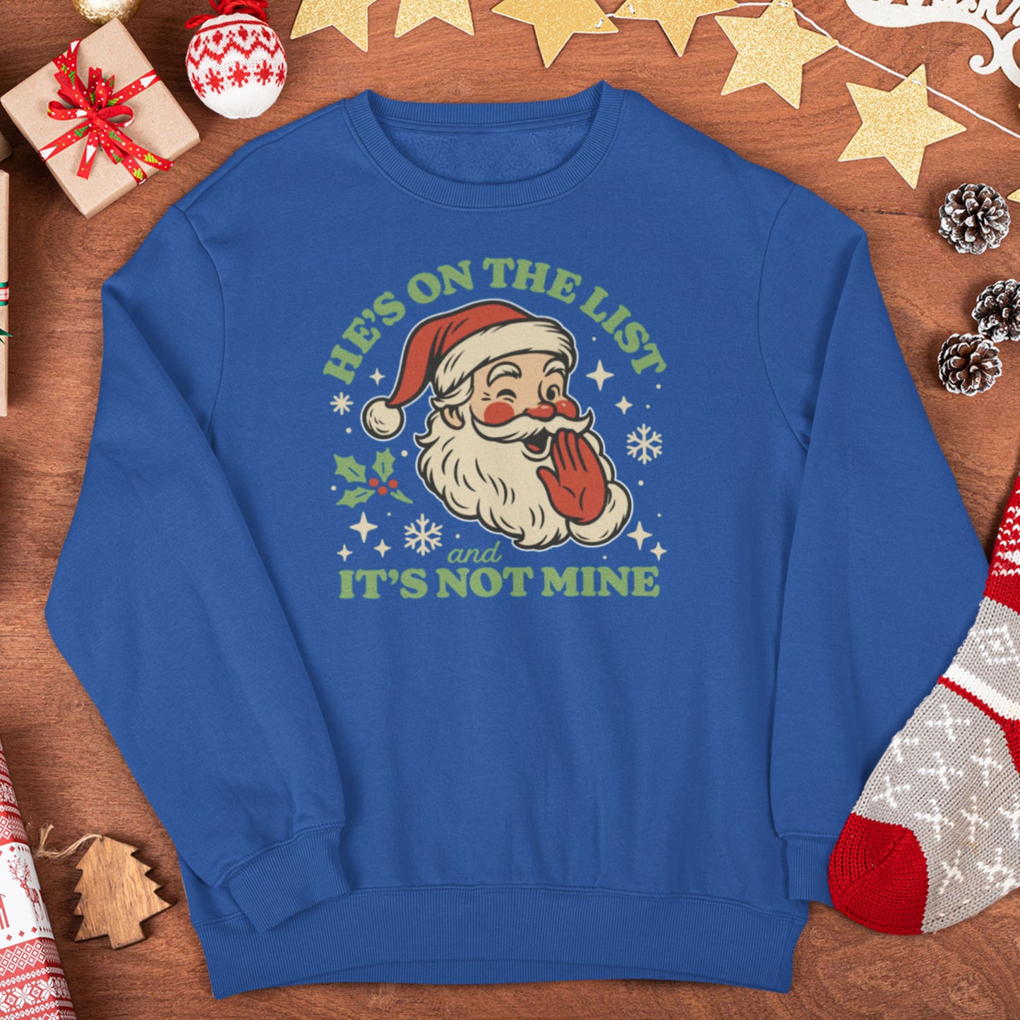 Royal blue unisex crewneck laid flat on a festive setting, showing the cheerful retro Santa graphic and lighthearted holiday phrase.