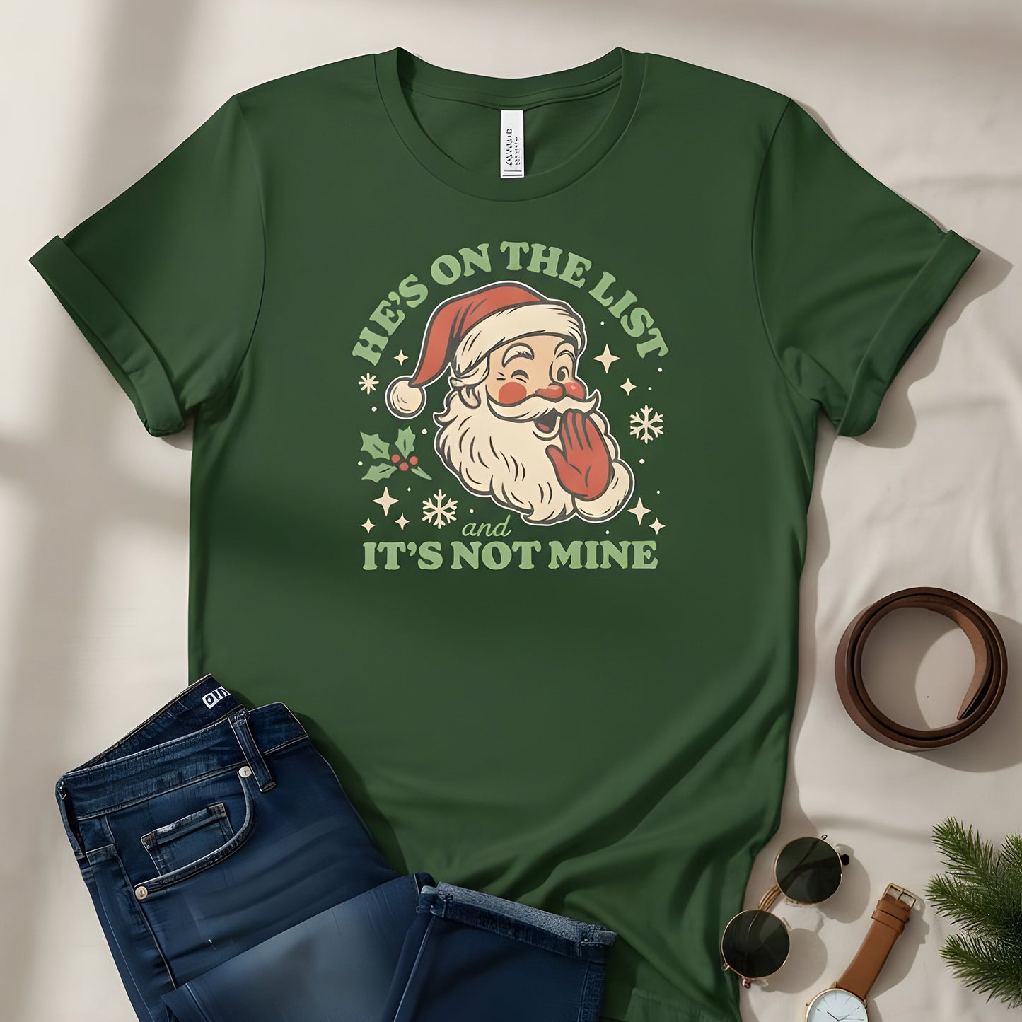 Forest green t-shirt with the vintage Santa artwork displayed in a cozy flat-lay scene with jeans, warm drinks, and holiday props.