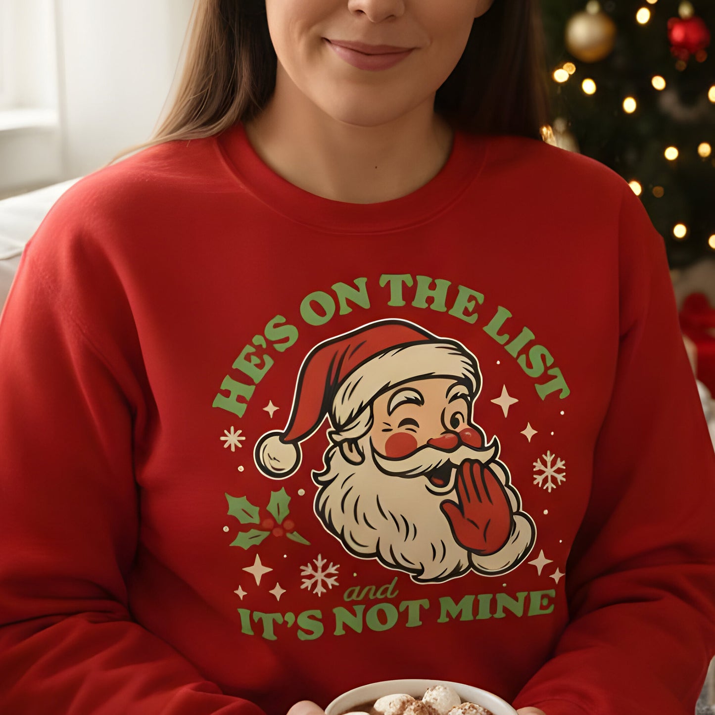A person wearing a red Christmas sweatshirt with the playful vintage Santa and “He’s On the List & It’s Not Mine” text, styled for a cozy holiday moment. A popular pick from Blue Wave USA.