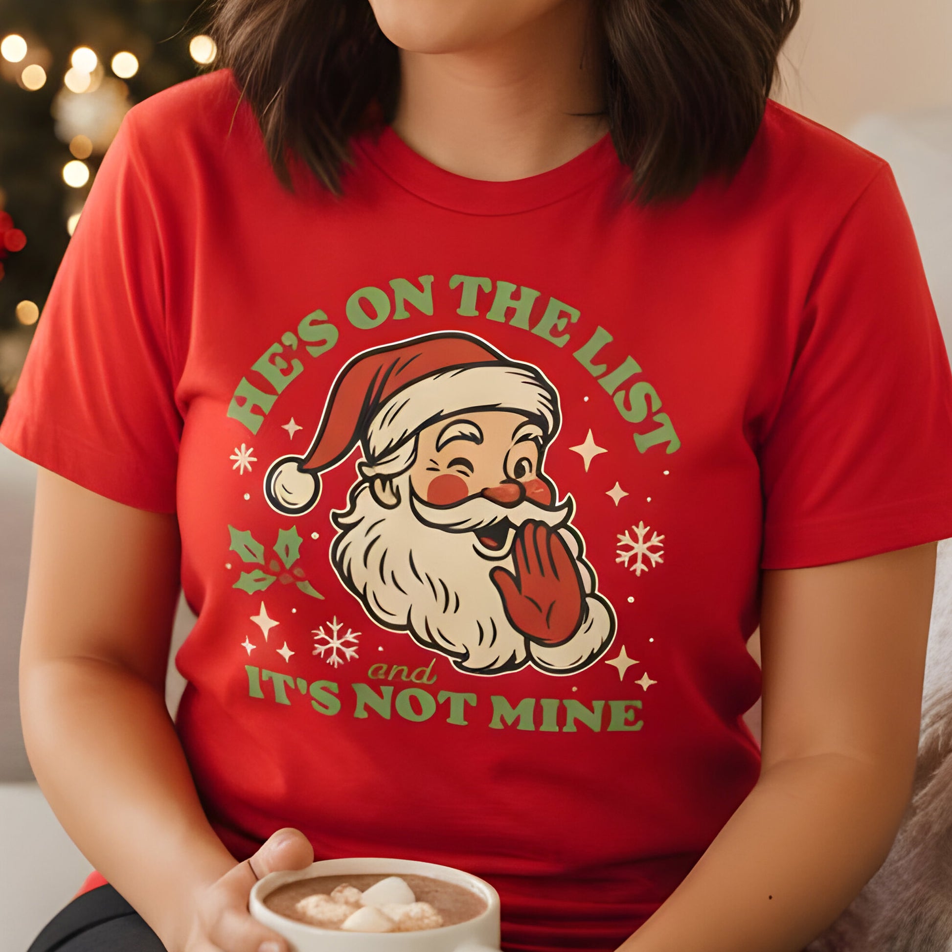 Person wearing a red t-shirt with the cheeky Santa “He’s On the List and It’s Not Mine” graphic, smiling while holding a holiday mug. A playful seasonal favorite from Blue Wave USA.