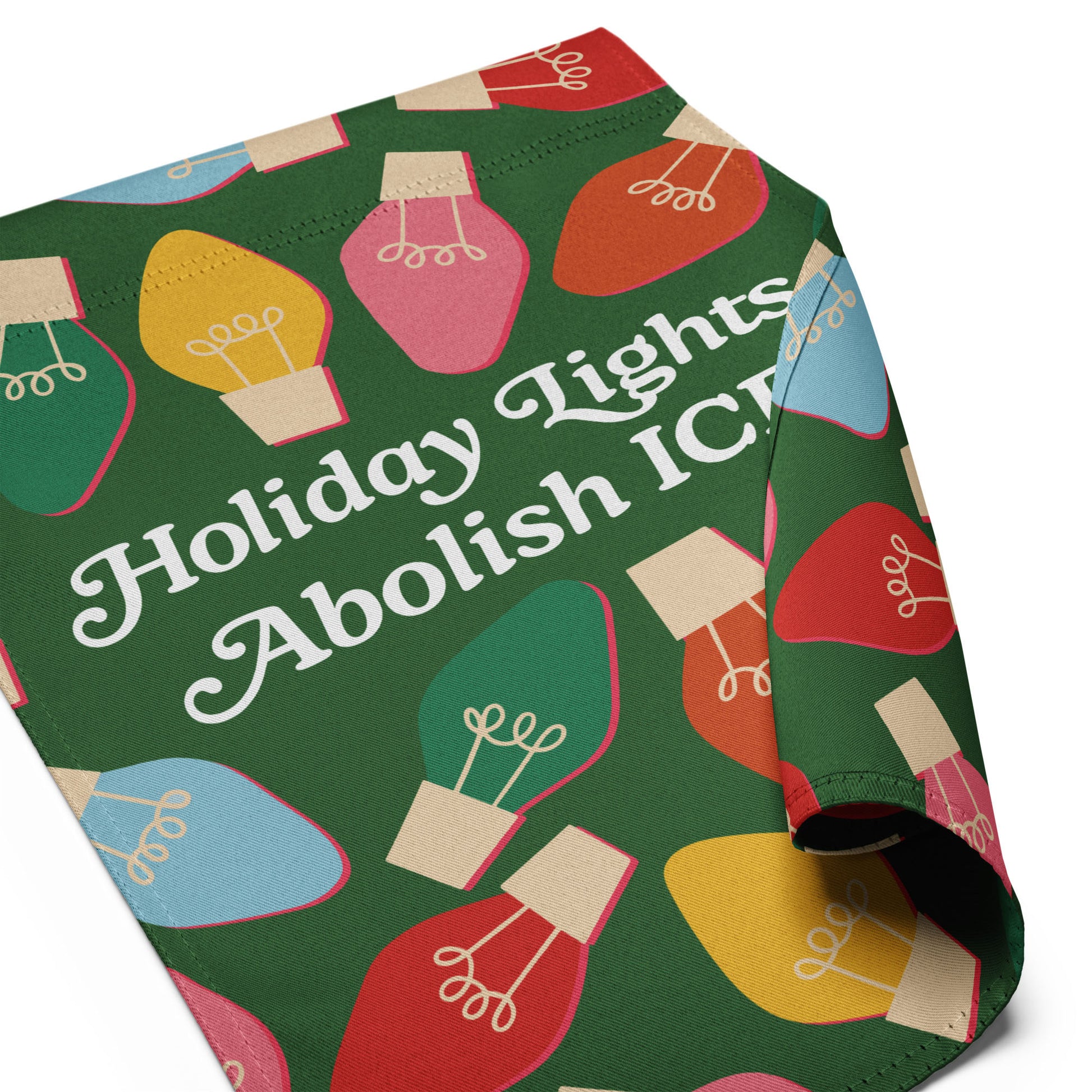 A folded view of the green garden flag showing the illustrated bulbs and typography from “Holiday Lights Abolish ICE,” highlighting print quality and cheerful seasonal activism.