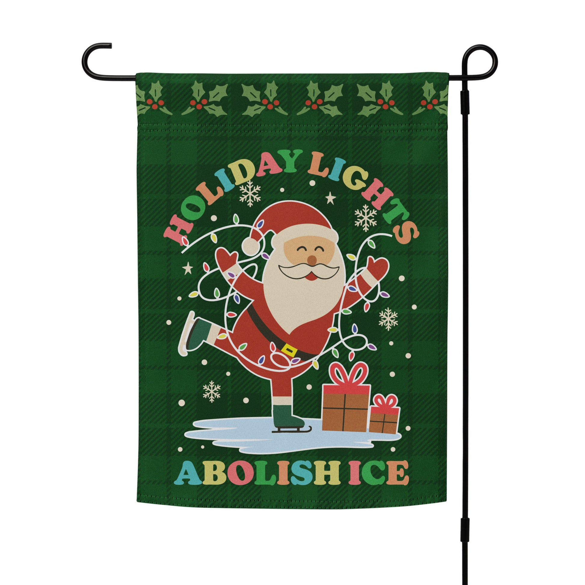 A green garden flag with Santa ice-skating beside bright holiday lights, stars, and gifts framing the message “HOLIDAY LIGHTS ABOLISH ICE,” photographed on a stand for holiday activism displays.