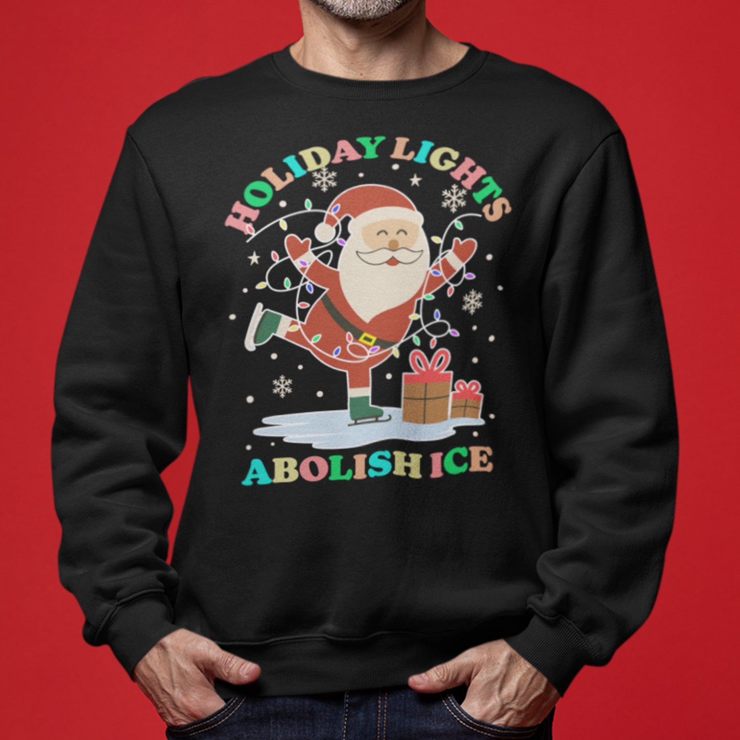 A model wearing a black unisex sweatshirt decorated with Santa, glowing lights, stars, and gifts framing the message “HOLIDAY LIGHTS ABOLISH ICE,” ideal for fun progressive Christmas outfits.
