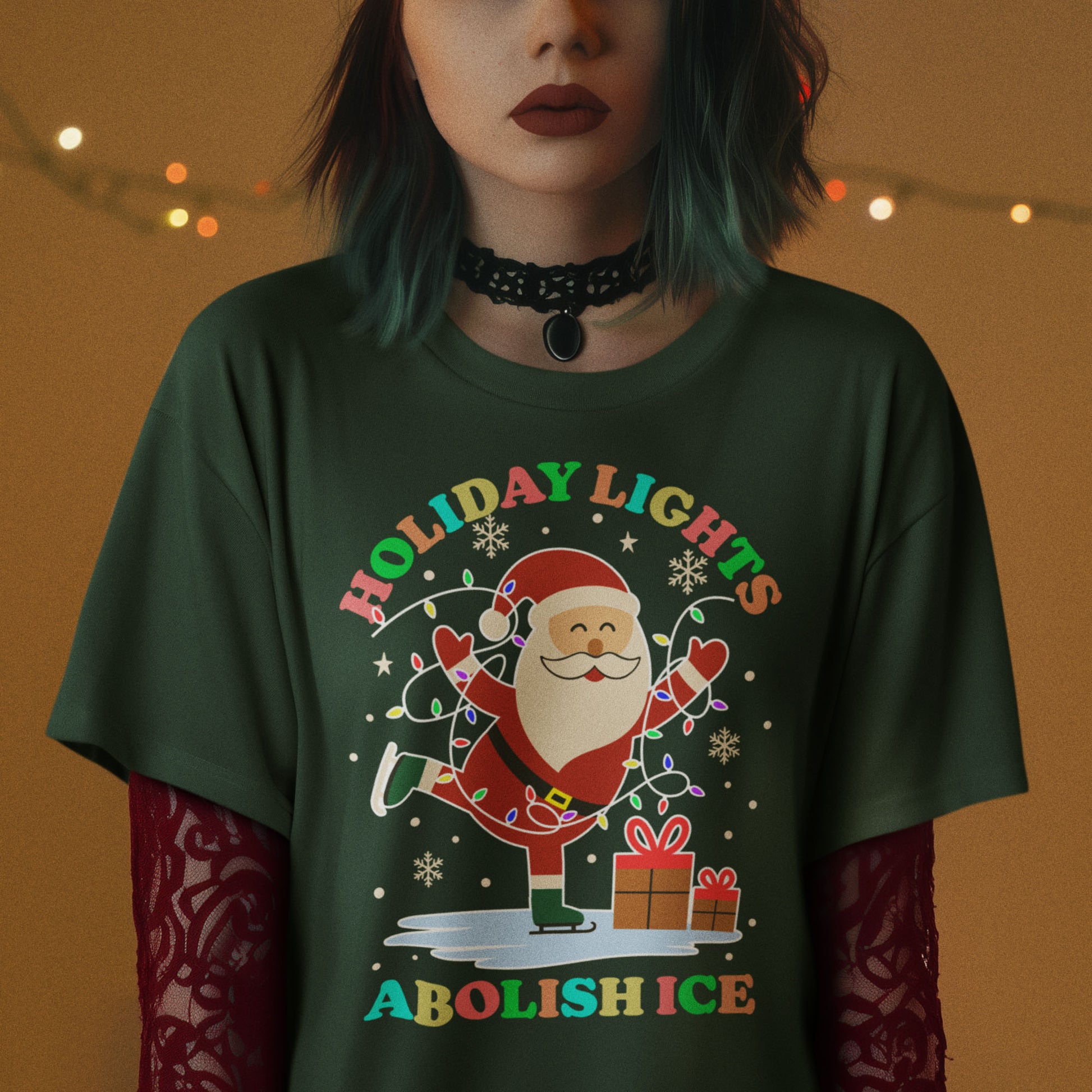 Person wearing a forest green t-shirt featuring Santa with gifts and lights, printed with “HOLIDAY LIGHTS ABOLISH ICE,” shown in warm indoor holiday lighting.