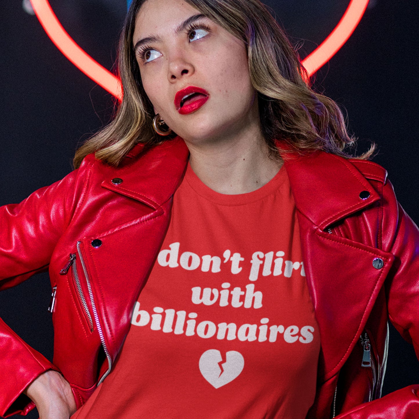 Red unisex t-shirt worn by a model, featuring bold white typography and broken-heart graphic with the phrase “i don’t flirt with billionaires,” styled as progressive apparel for Valentine’s Day.