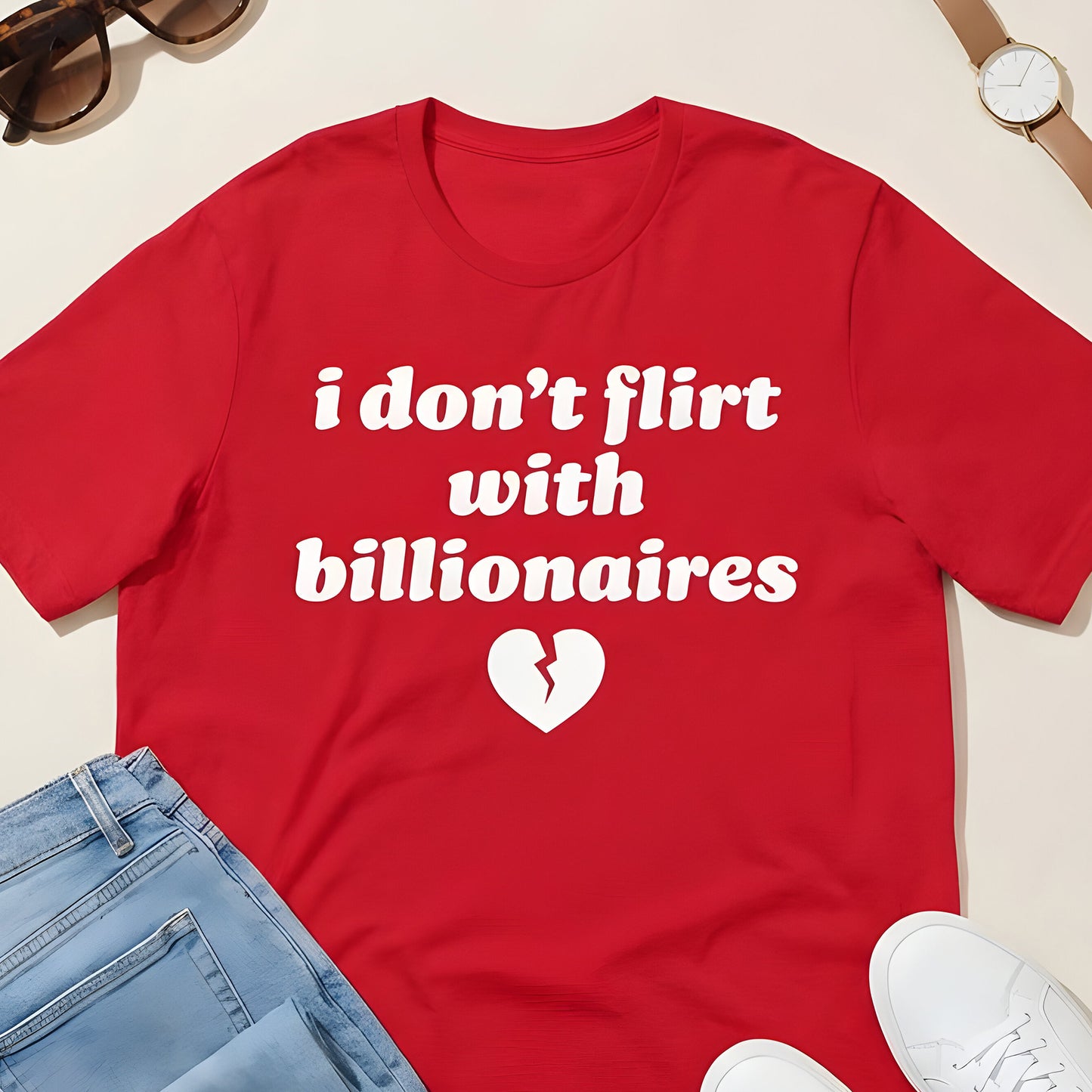 Red unisex t-shirt flat lay with jeans and accessories, displaying bold white text and heart graphic reading “i don’t flirt with billionaires,” a justice-focused design by Blue Wave USA.