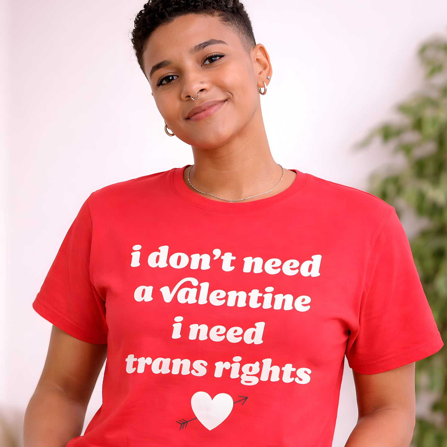 Unisex t-shirt worn by smiling model, bold white typographic artwork reads “i don’t need a Valentine i need trans rights,” progressive Valentine design celebrating trans rights and visibility.