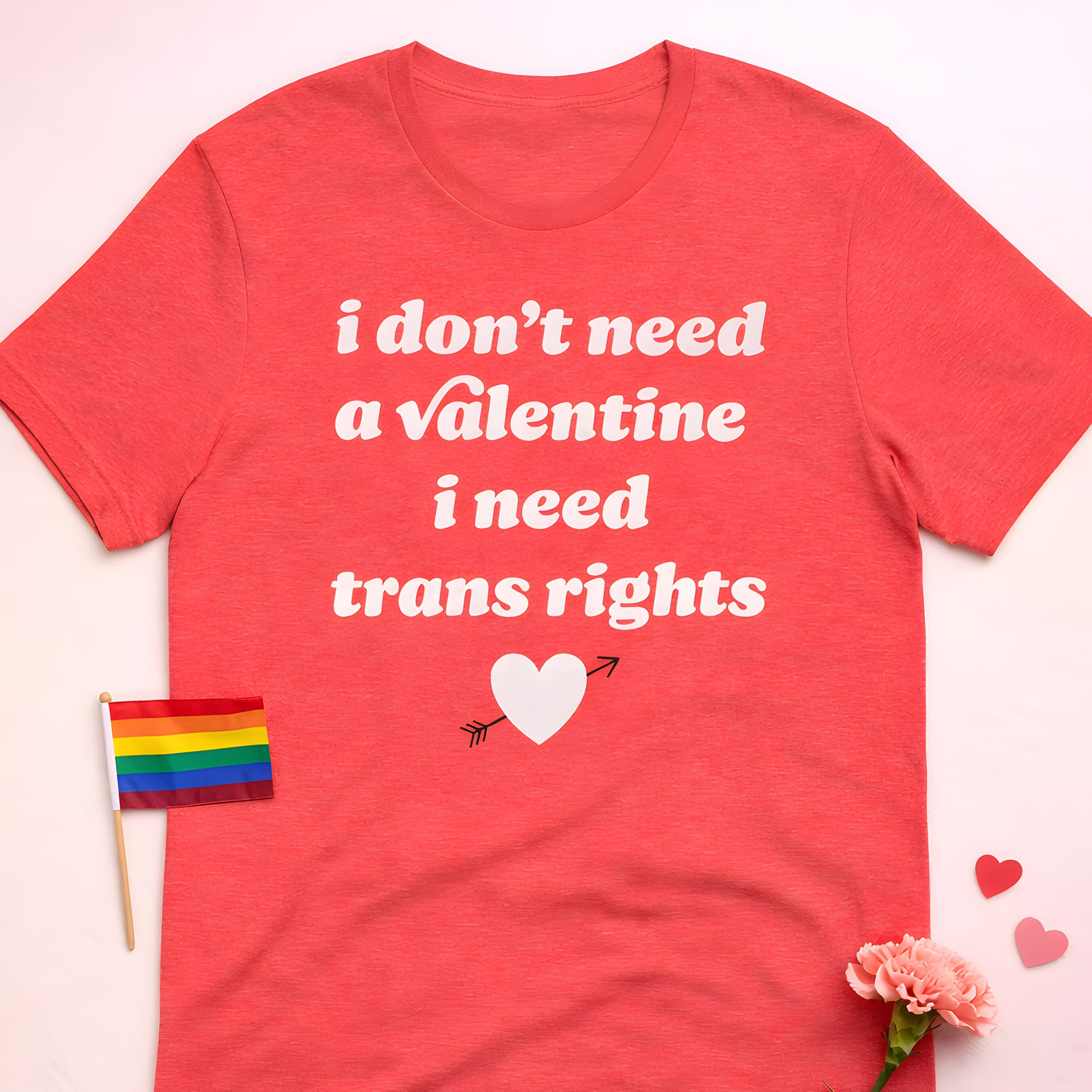 Unisex t-shirt laid flat with rainbow flag accent, graphic typography displays “i don’t need a Valentine i need trans rights,” justice-focused design from Blue Wave USA.