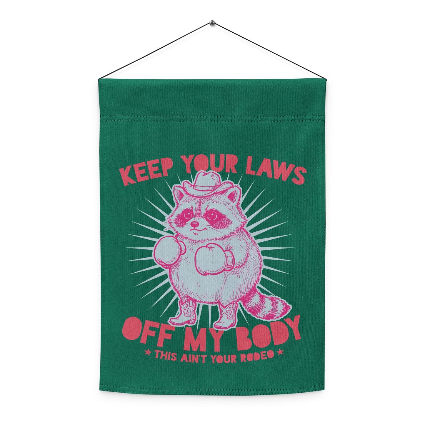 Hanging green garden flag displaying pink raccoon cowboy artwork with “Keep Your Laws Off My Body” phrase in bold feminist activist design.