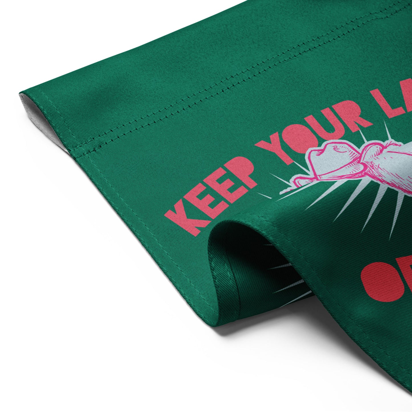 Close-up folded garden flag corner showing green fabric with partial raccoon illustration and visible “Keep Your Laws” protest wording detail.