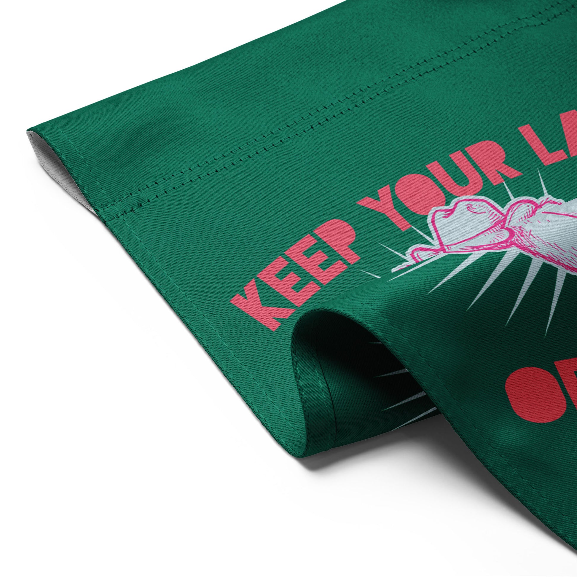 Close-up folded garden flag corner showing green fabric with partial raccoon illustration and visible “Keep Your Laws” protest wording detail.