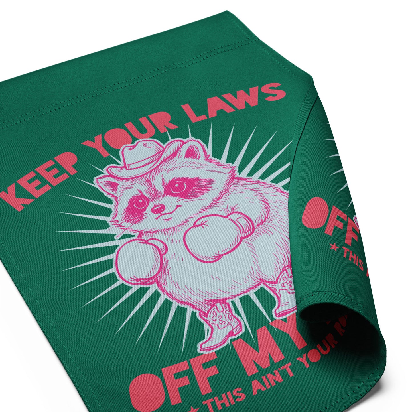 Folded green garden flag displaying partial raccoon cowboy artwork with visible “Off My Body” phrase in strong activist design.