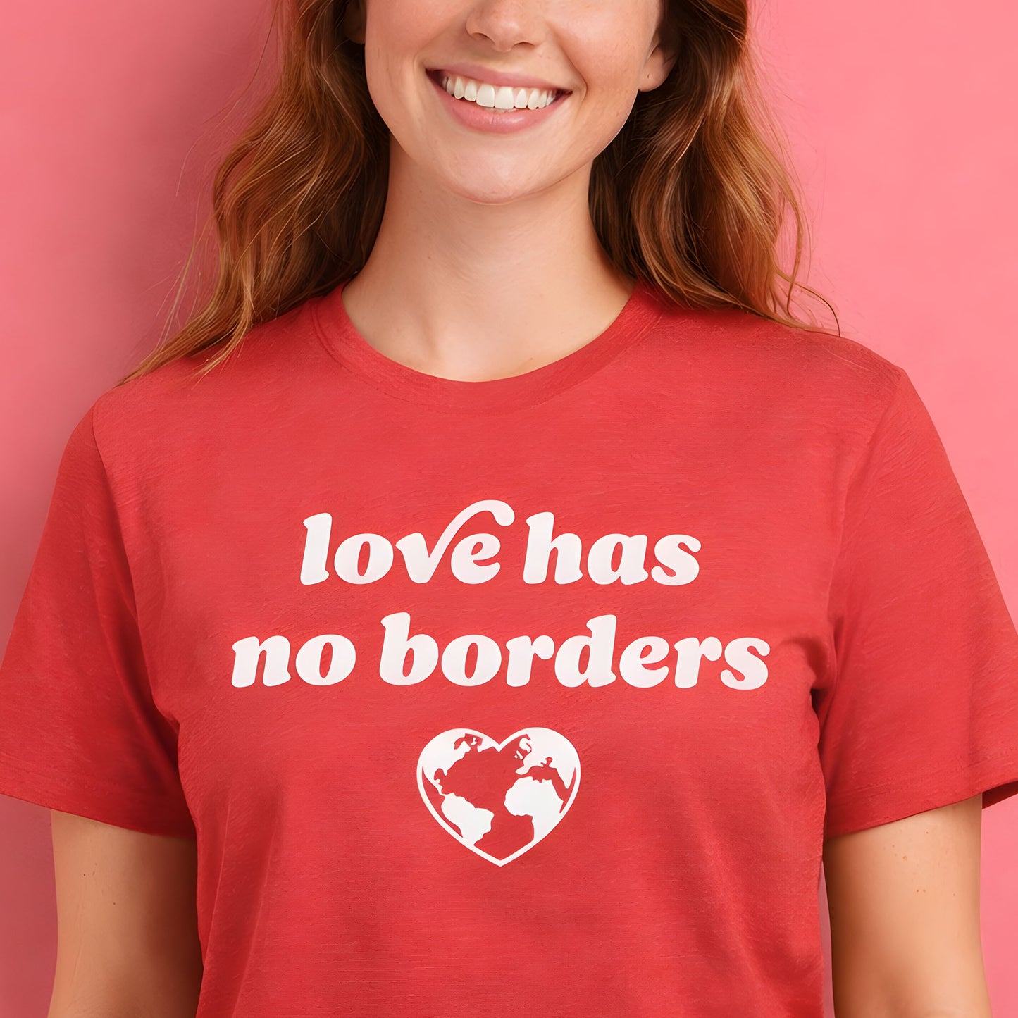 Model wearing red unisex t-shirt with bold white typography and globe heart graphic reading “love has no borders,” a justice-focused design by Blue Wave USA.