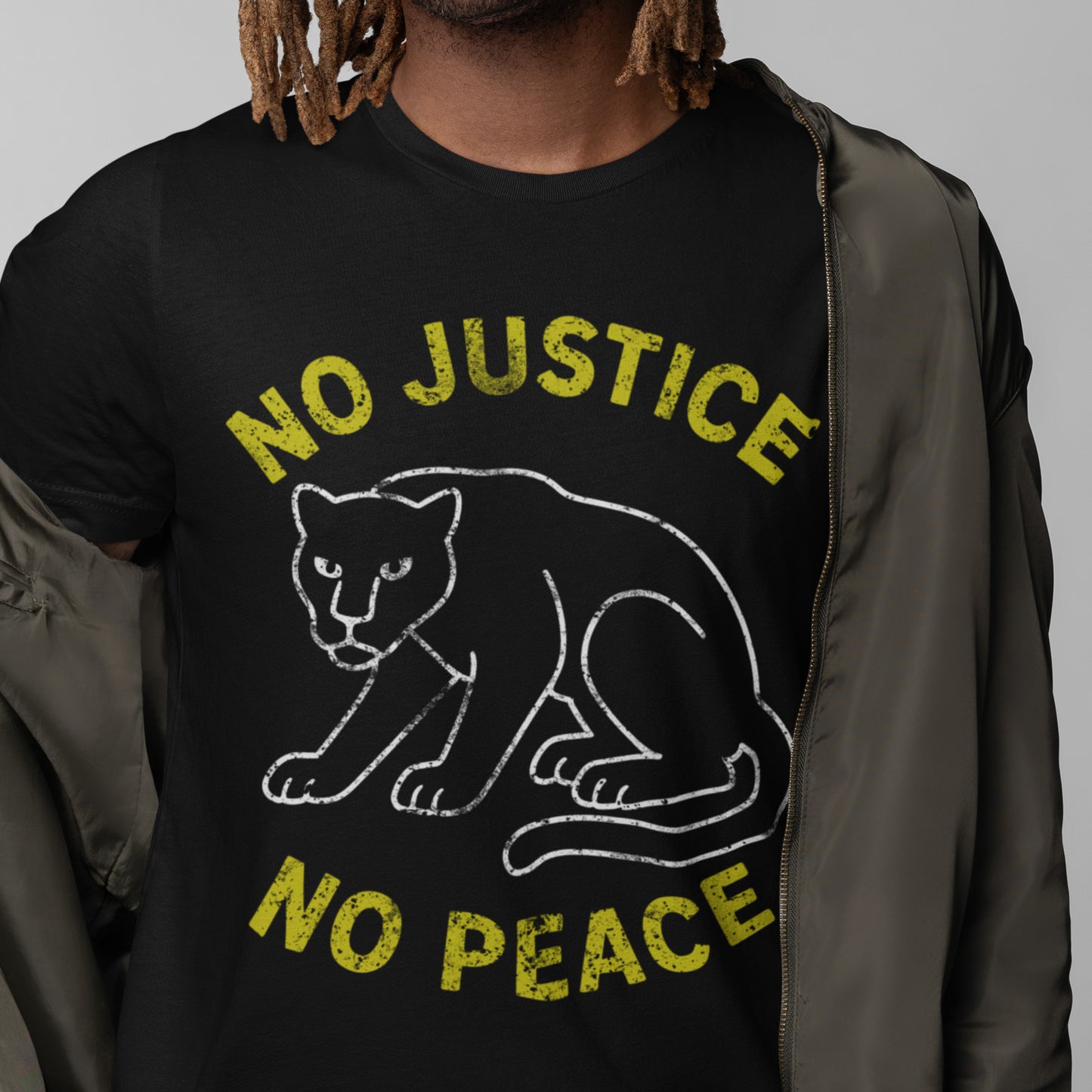 Model wearing a black unisex t-shirt with “NO JUSTICE NO PEACE” and a distressed panther graphic. Activist clothing highlighting justice-focused design.