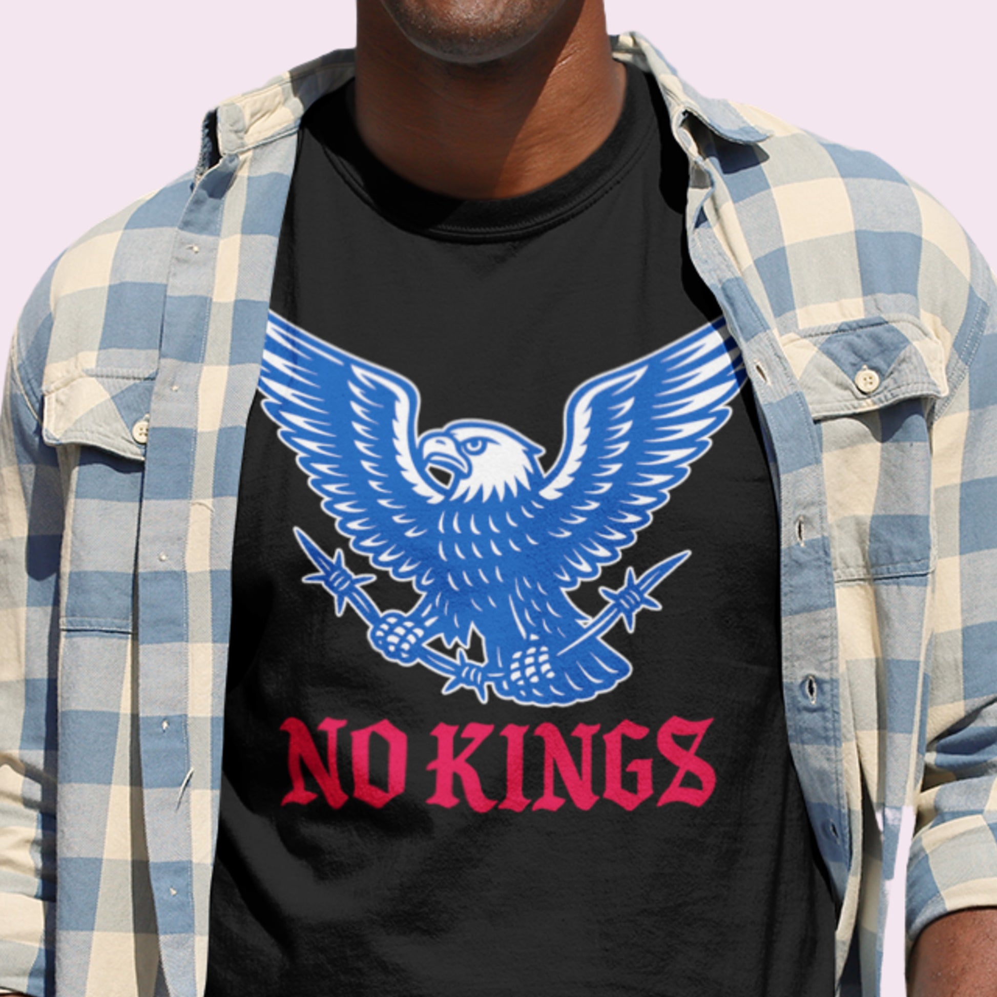 Person wearing the black “No Kings” t-shirt layered under a plaid shirt. A casual statement piece from Blue Wave USA that pairs activism with everyday style.