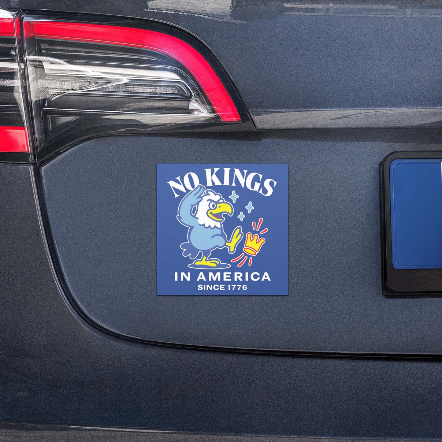 Square car magnet with eagle illustration and “NO KINGS IN AMERICA SINCE 1776” message displayed on vehicle trunk.