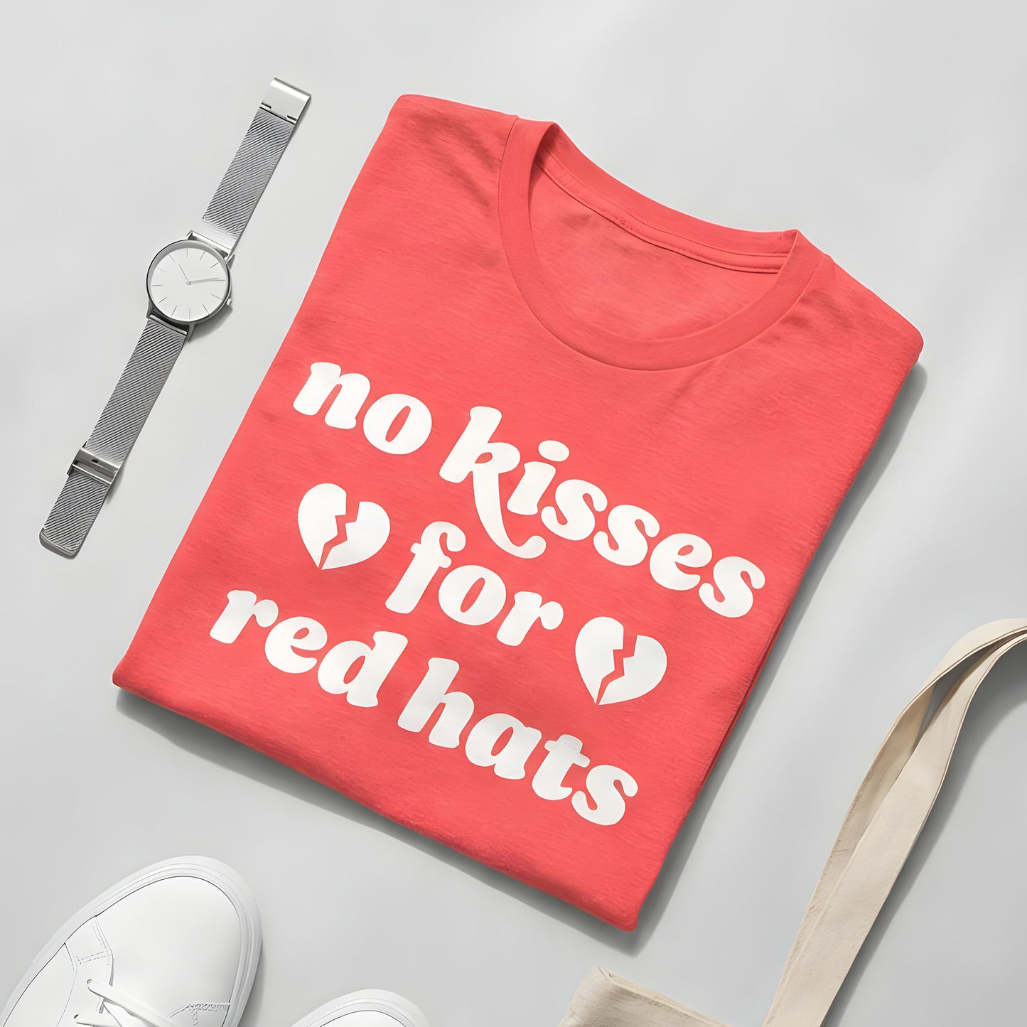Heather Red unisex anti-MAGA t-shirt folded flat featuring bold white text reading “no kisses for red hats,” broken heart icons, styled with watch and sneakers on a neutral background, progressive apparel.