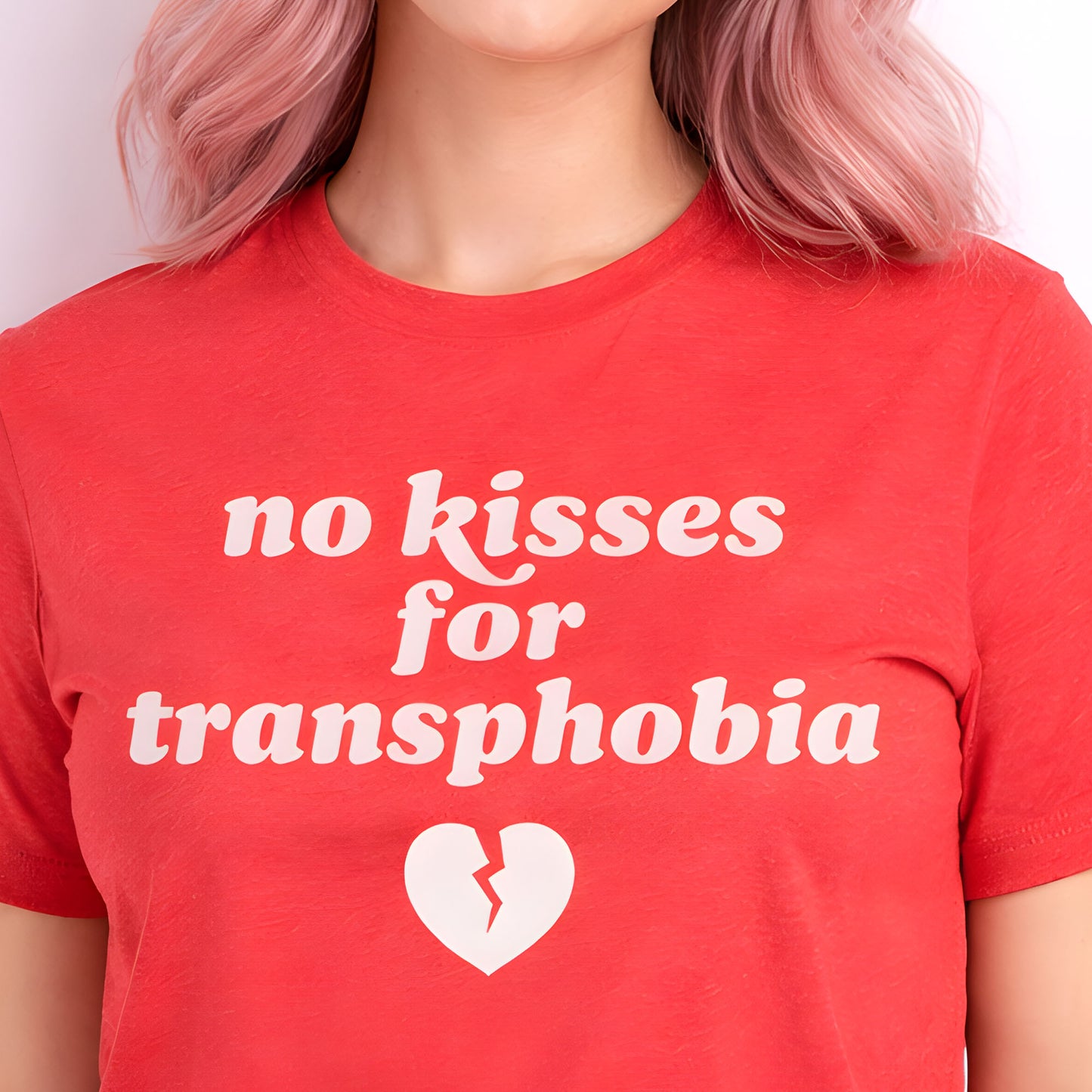Heather red unisex t-shirt worn by model, featuring bold retro typography and broken heart graphic with the phrase “no kisses for transphobia,” a justice-focused design by Blue Wave USA.