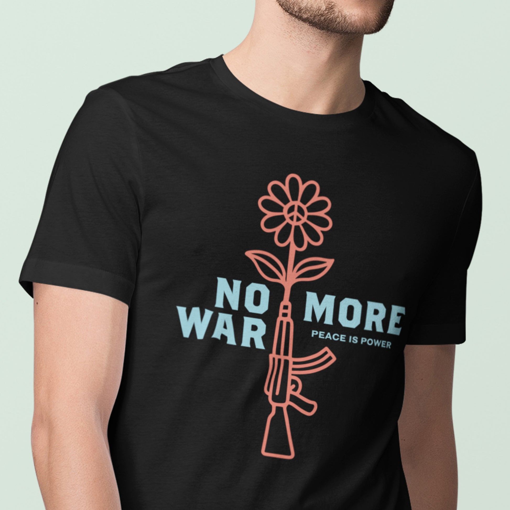 Model wearing black unisex t-shirt with flower growing from rifle illustration and “NO MORE WAR” message in clean typographic layout.