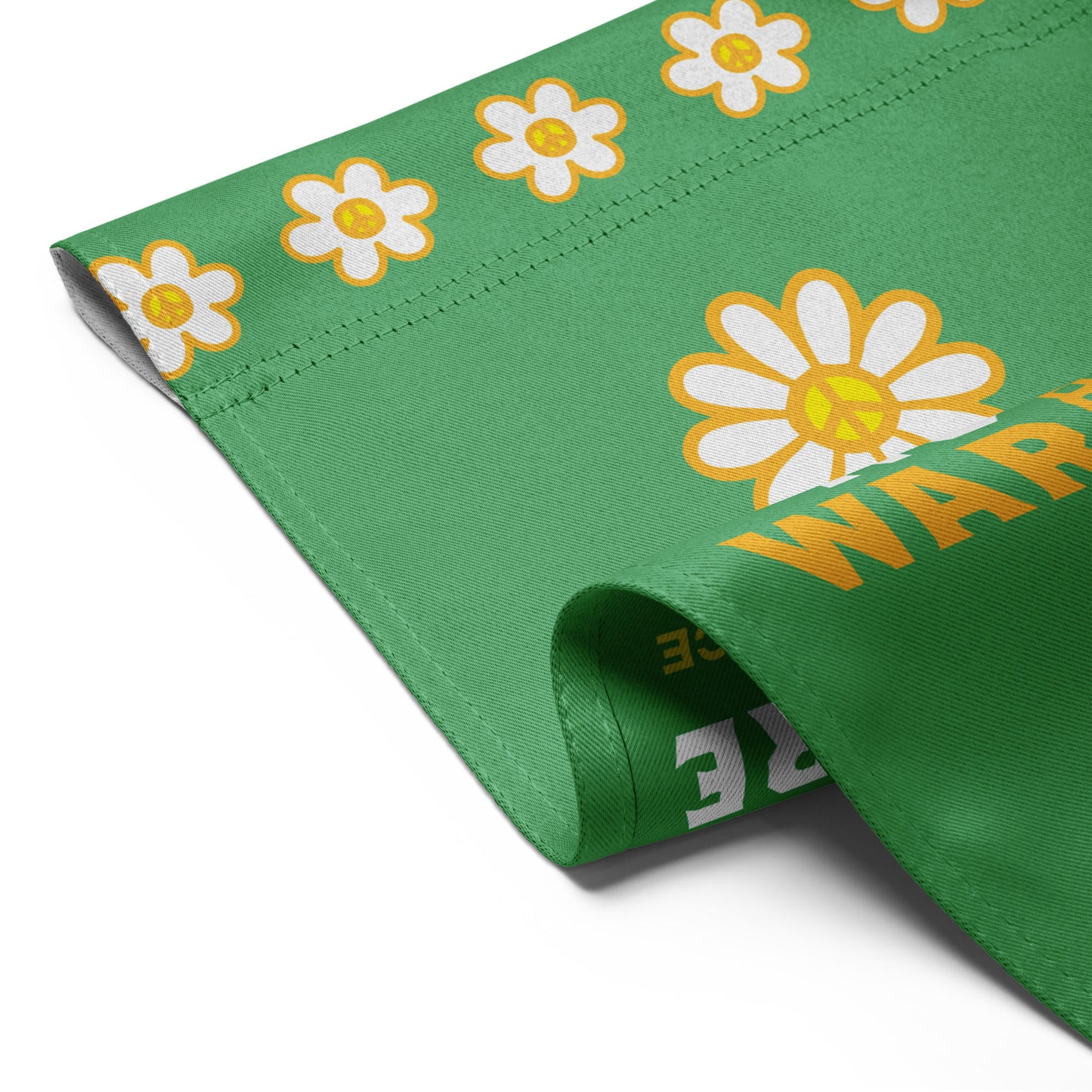 Close-up of green garden flag fabric featuring bright floral rifle design and partial “NO MORE WAR” text in clean, justice-focused layout.