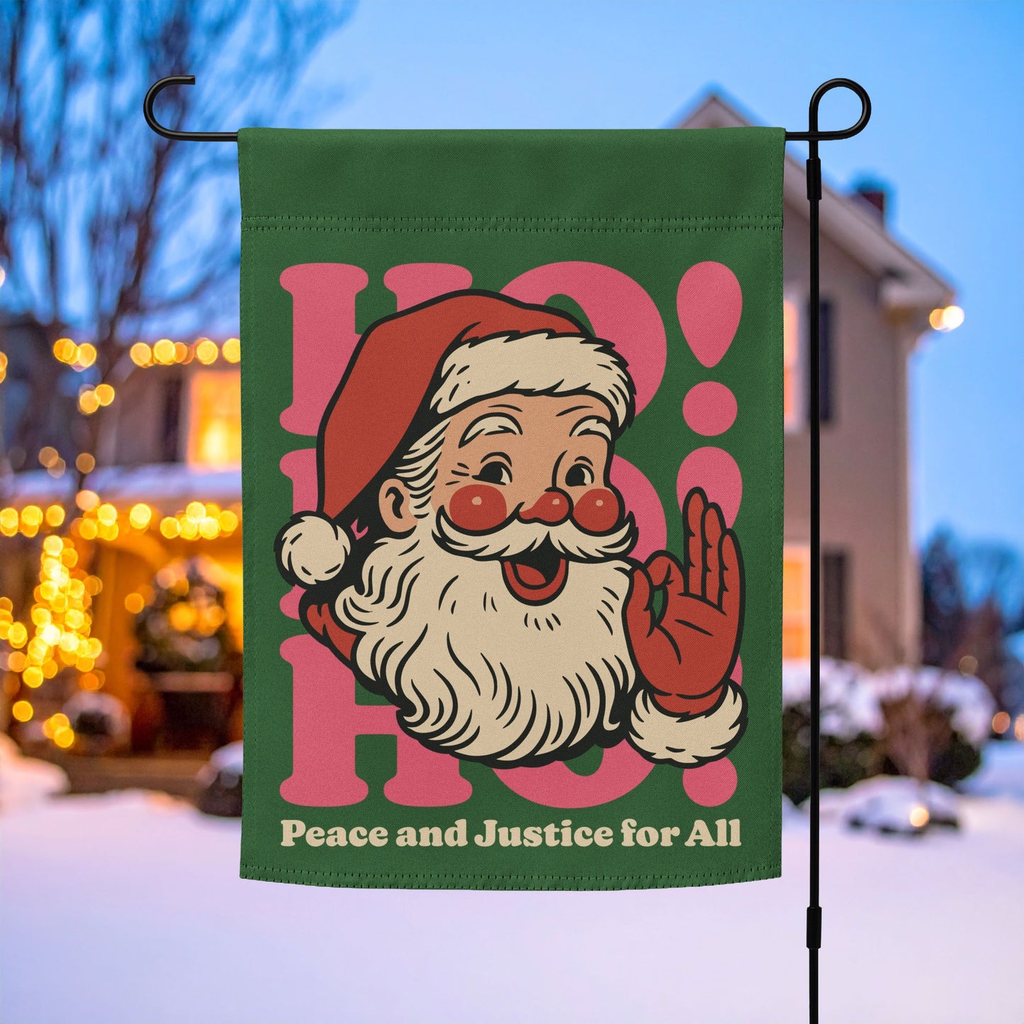 Green garden flag on a metal stand featuring a retro Santa illustration with pink “HO!” lettering and the printed message “Peace and Justice for All,” holiday outdoor décor by Blue Wave USA.