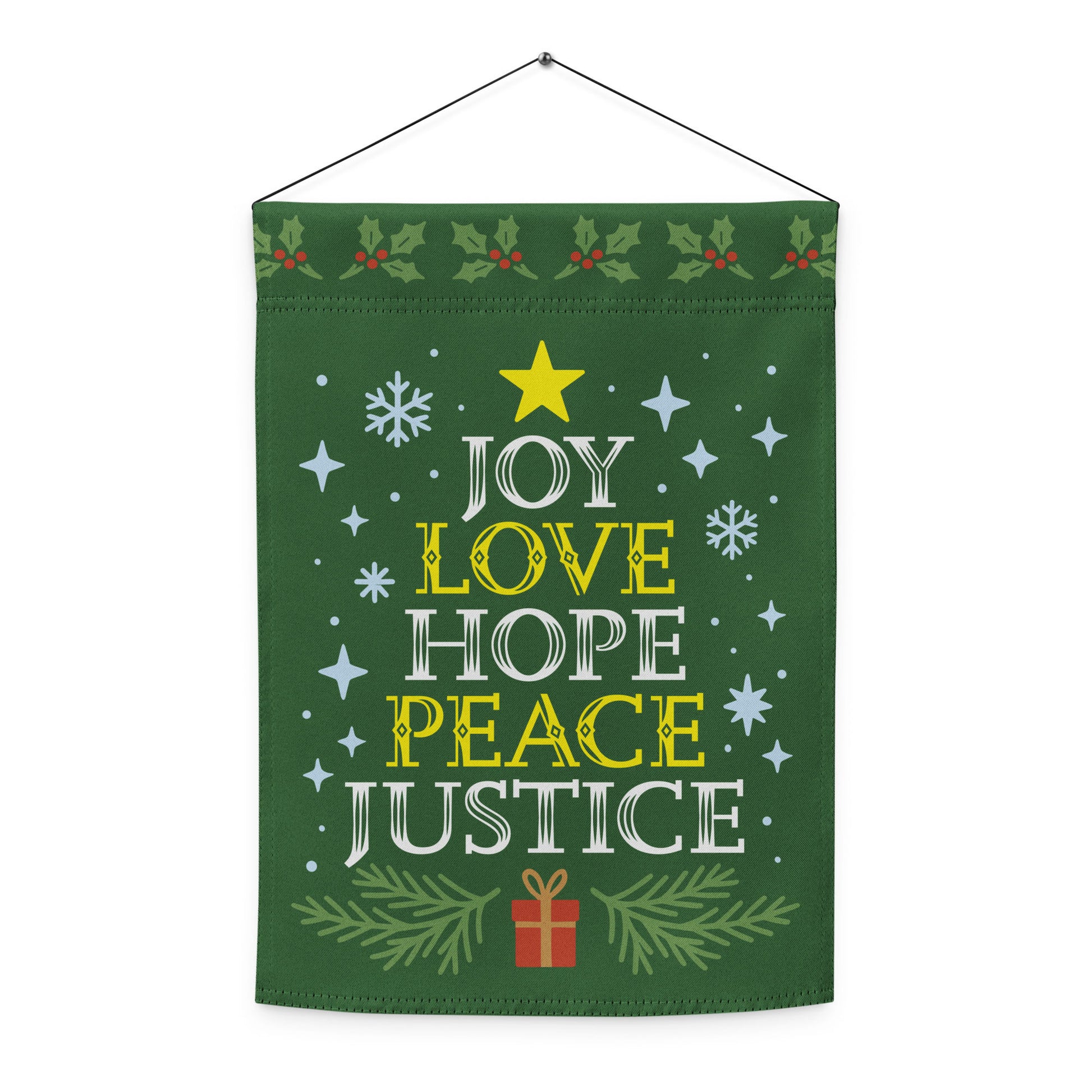 Green hanging garden flag showing festive stars, snowflakes, a gift box, and the printed message “JOY LOVE HOPE PEACE JUSTICE,” designed by Blue Wave USA.