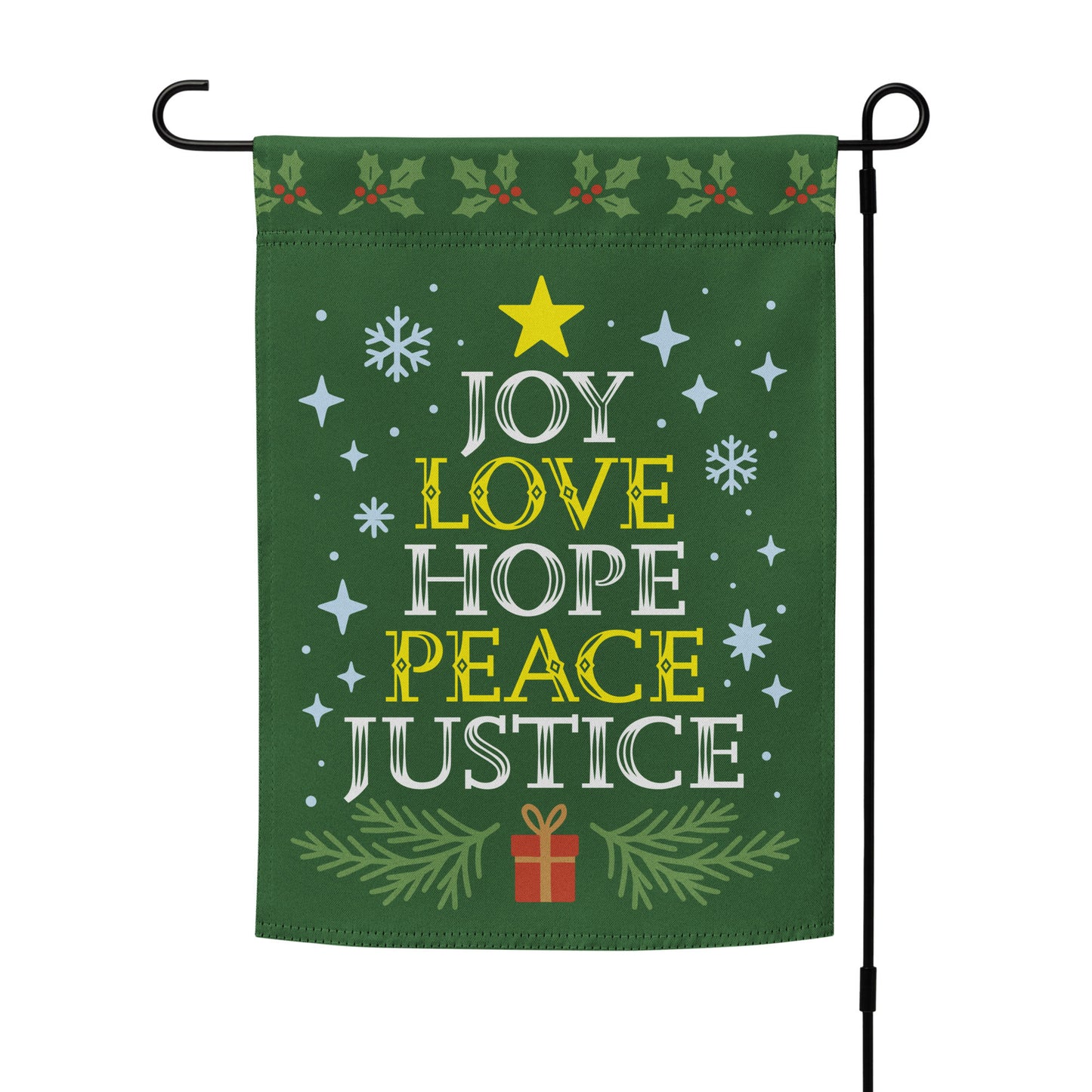 Green garden flag on a metal stand with holiday accents and bold white and yellow text reading “JOY LOVE HOPE PEACE JUSTICE,” framed by stars and greenery.